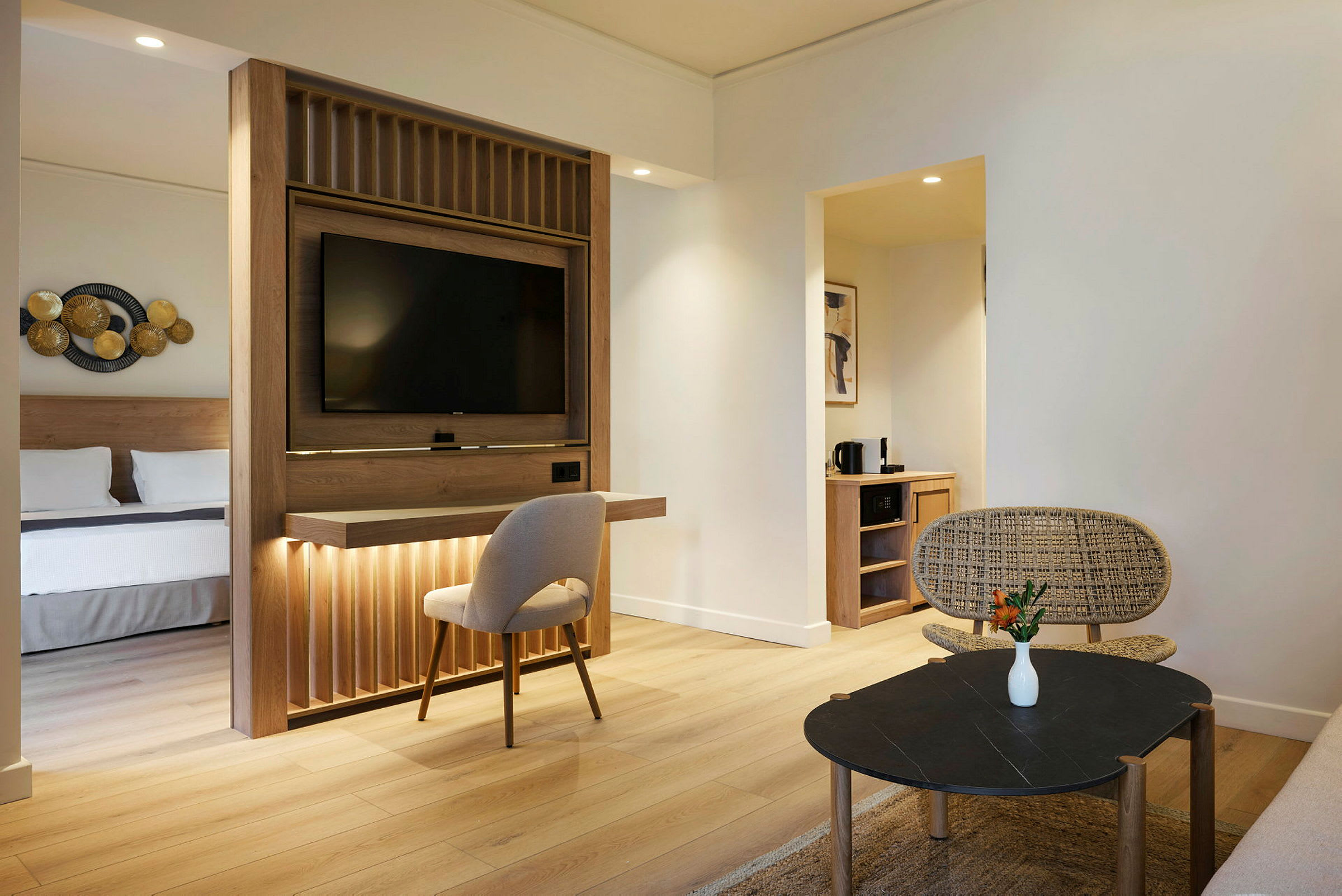 Hotellrum med modern inredning, separat sovplats och vardagsrum med sittmöbler och bord. (AI-genererad text)
