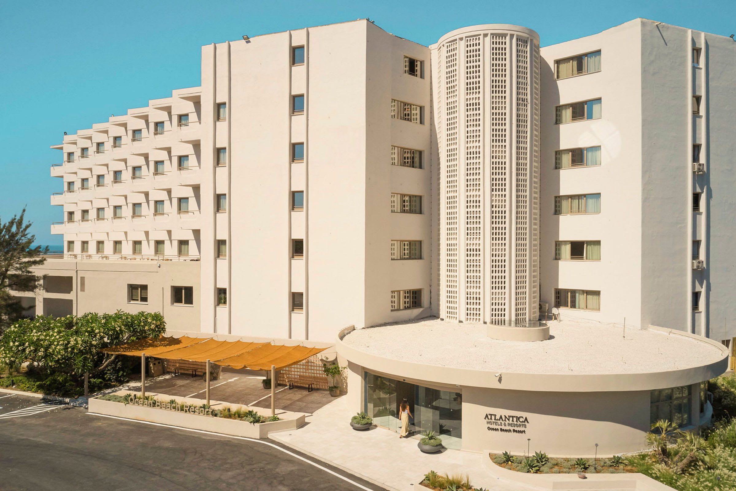 Vitmodern byggnad med flera våningar och ett hotellnamn synligt vid ingången. (AI-genererad text)