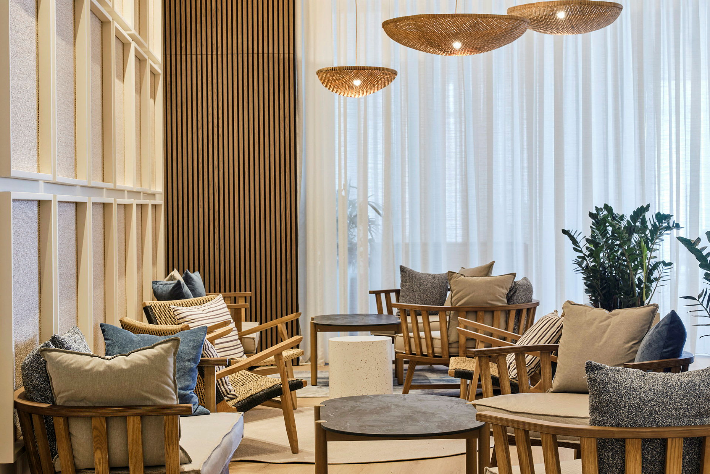 En stilfull lounge med träfåtöljer, kuddar och låga bord. (AI-genererad text)