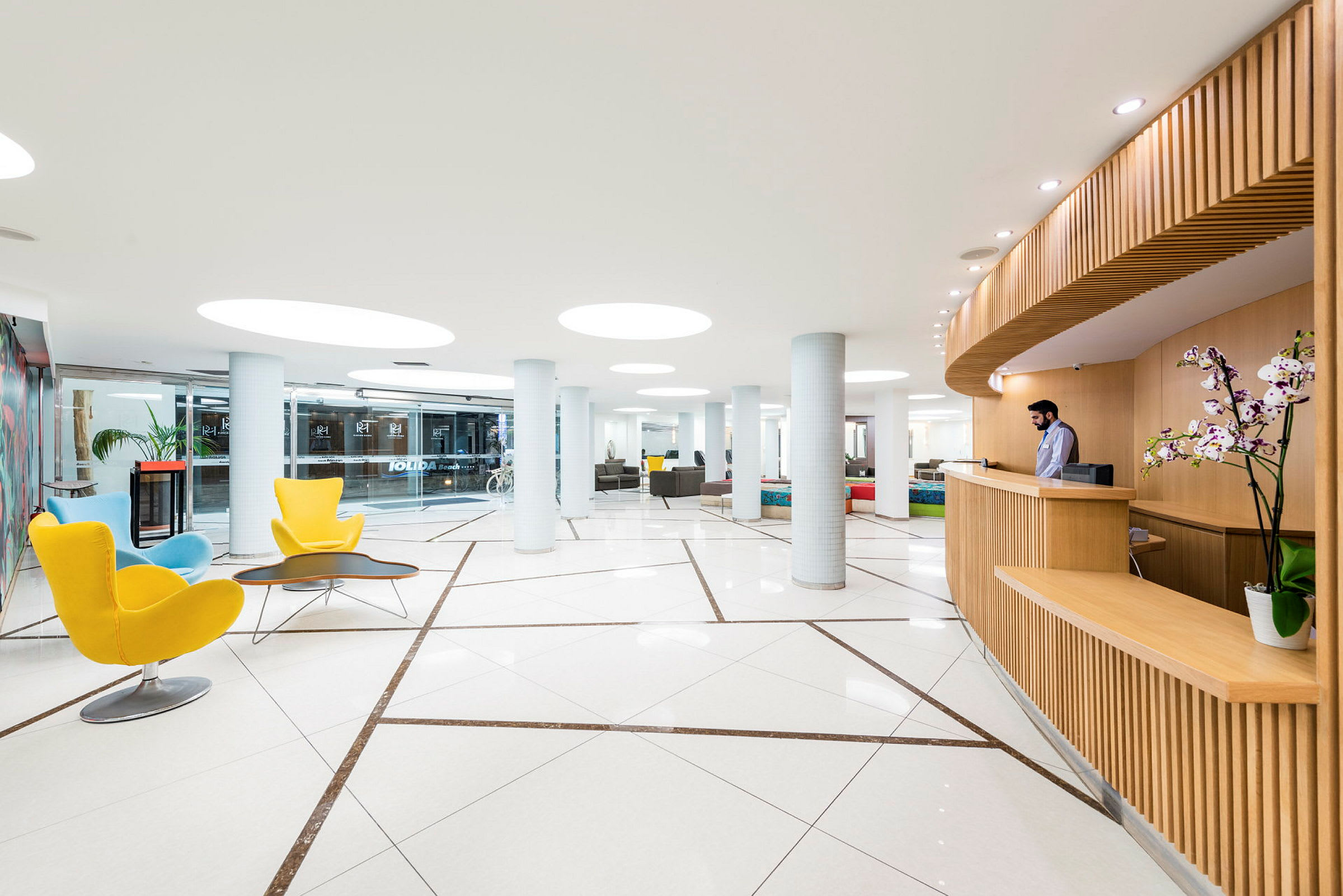 Modern hotellobby med ljusa möbler, trädetaljer och glastak. (AI-genererad text)