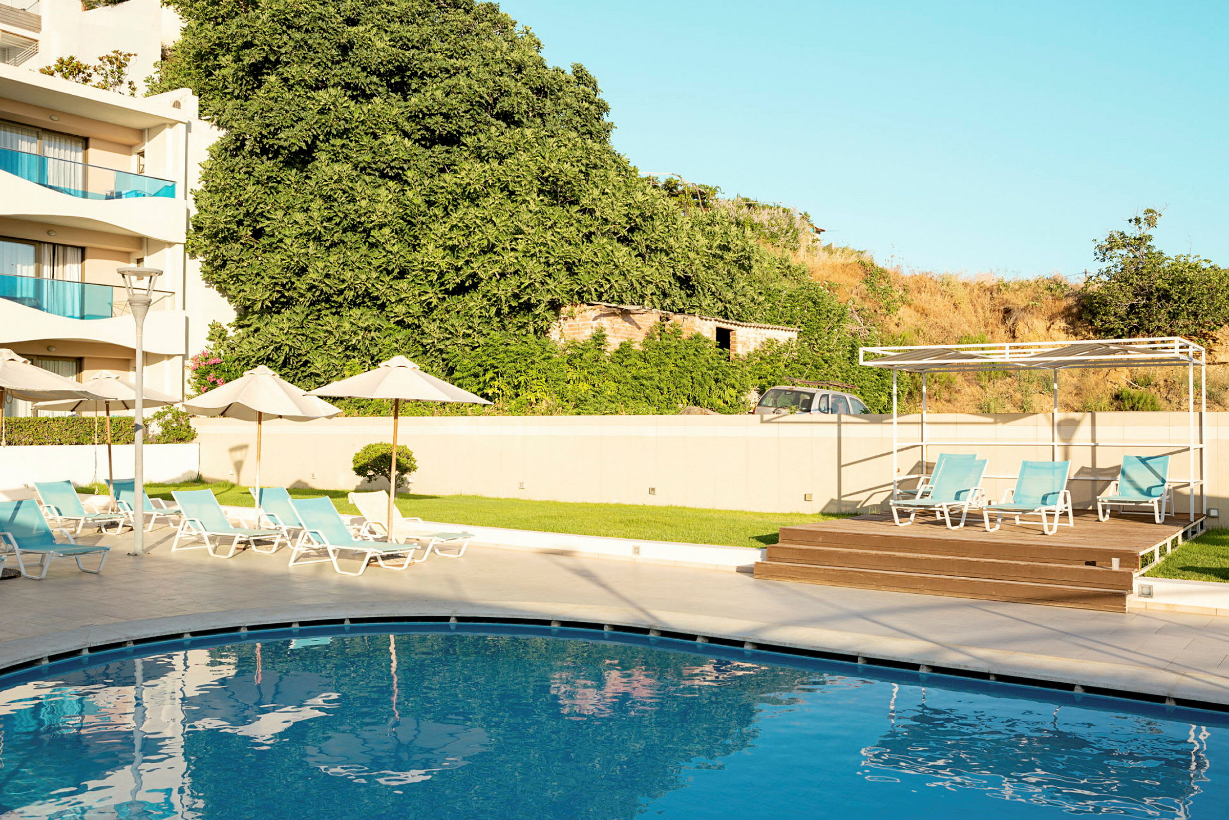 En swimmingpool med solstolar i en hotellmiljö. (AI-genererad text)