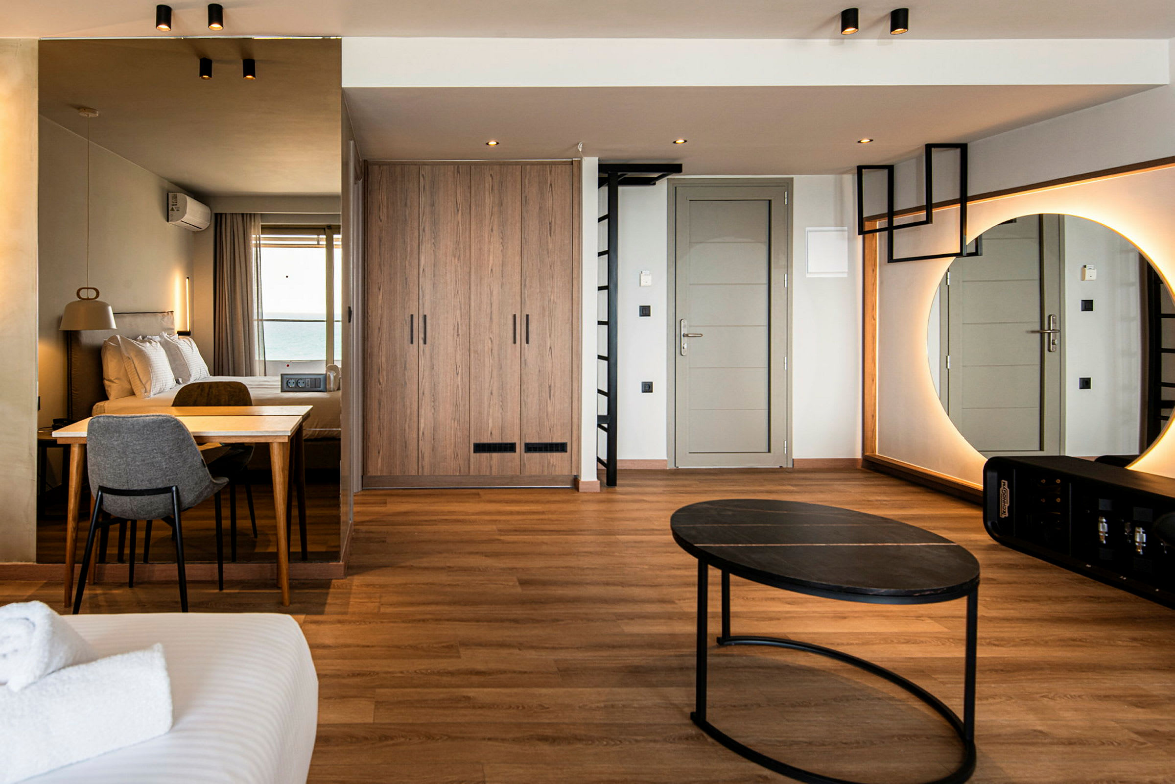 Hotellrum med modern inredning, inklusive säng, bord, stol, spegel och garderob. (AI-genererad text)