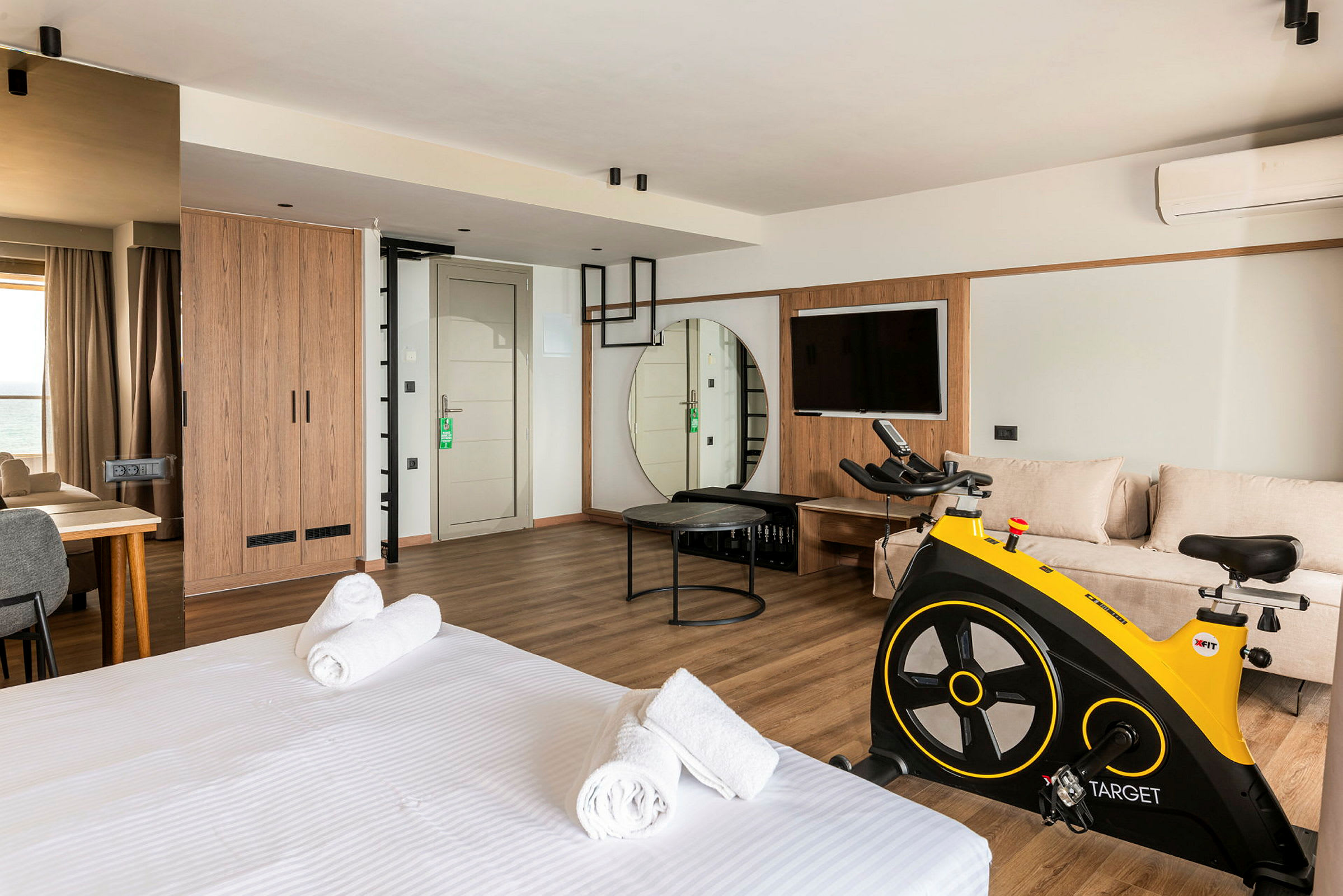 Ett modernt hotellrum med säng, sittgrupp, motionscykel och TV. (AI-genererad text)