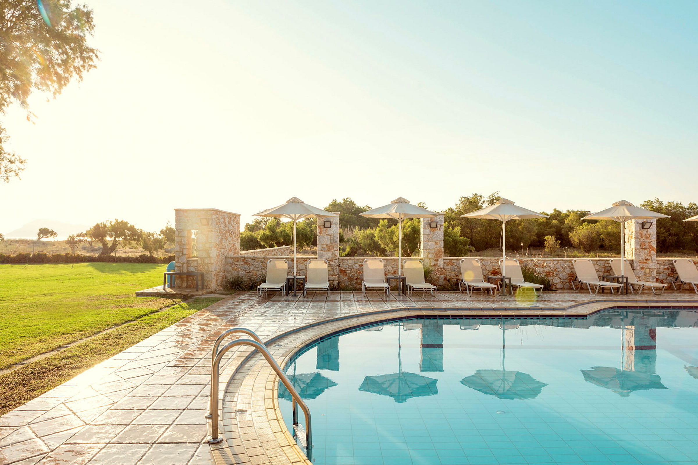 Utemiljö med en pool och solstolar med parasoller. (AI-genererad text)