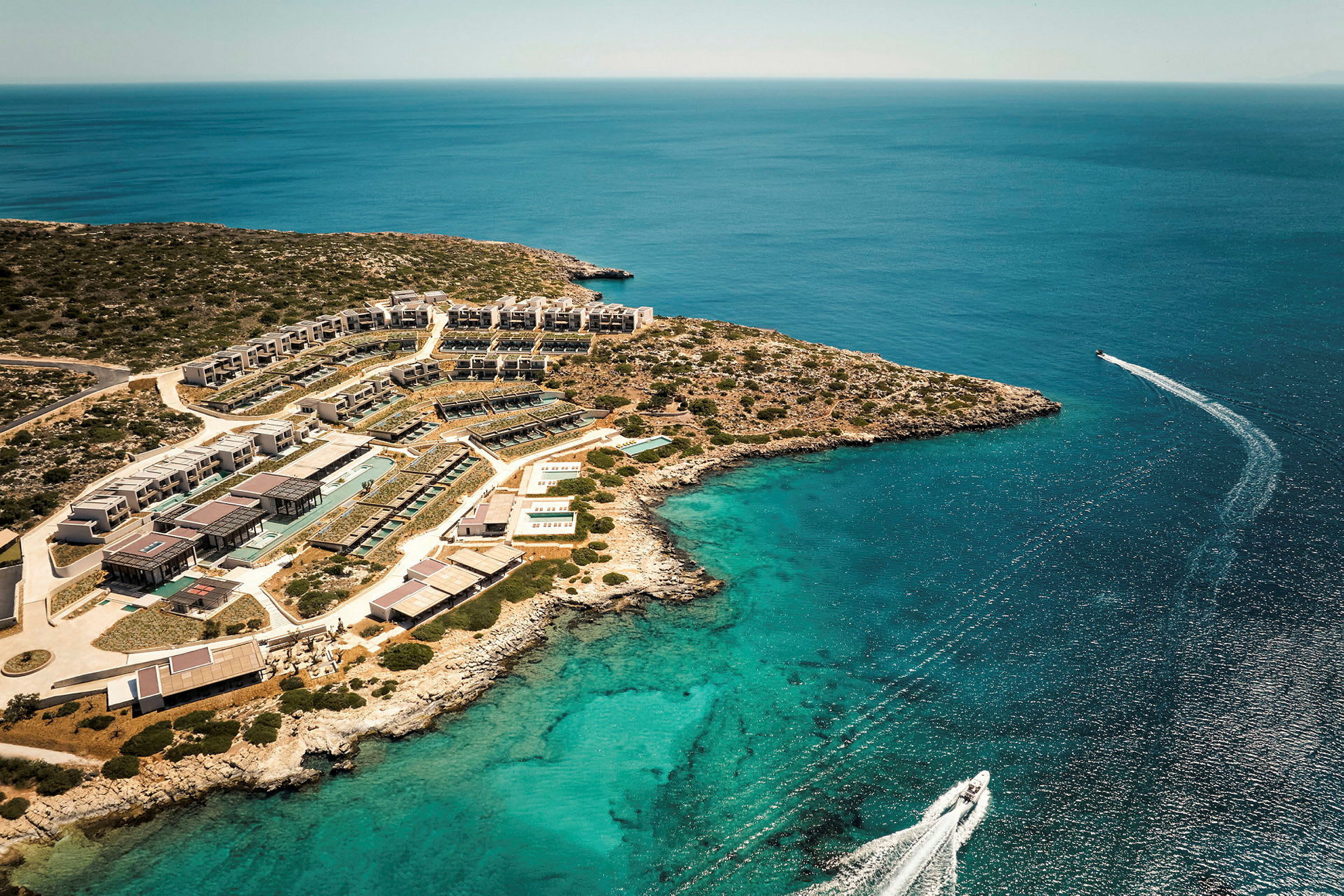 Ett flygfotografi av en resort vid havet med en båt i vatten. (AI-genererad text)