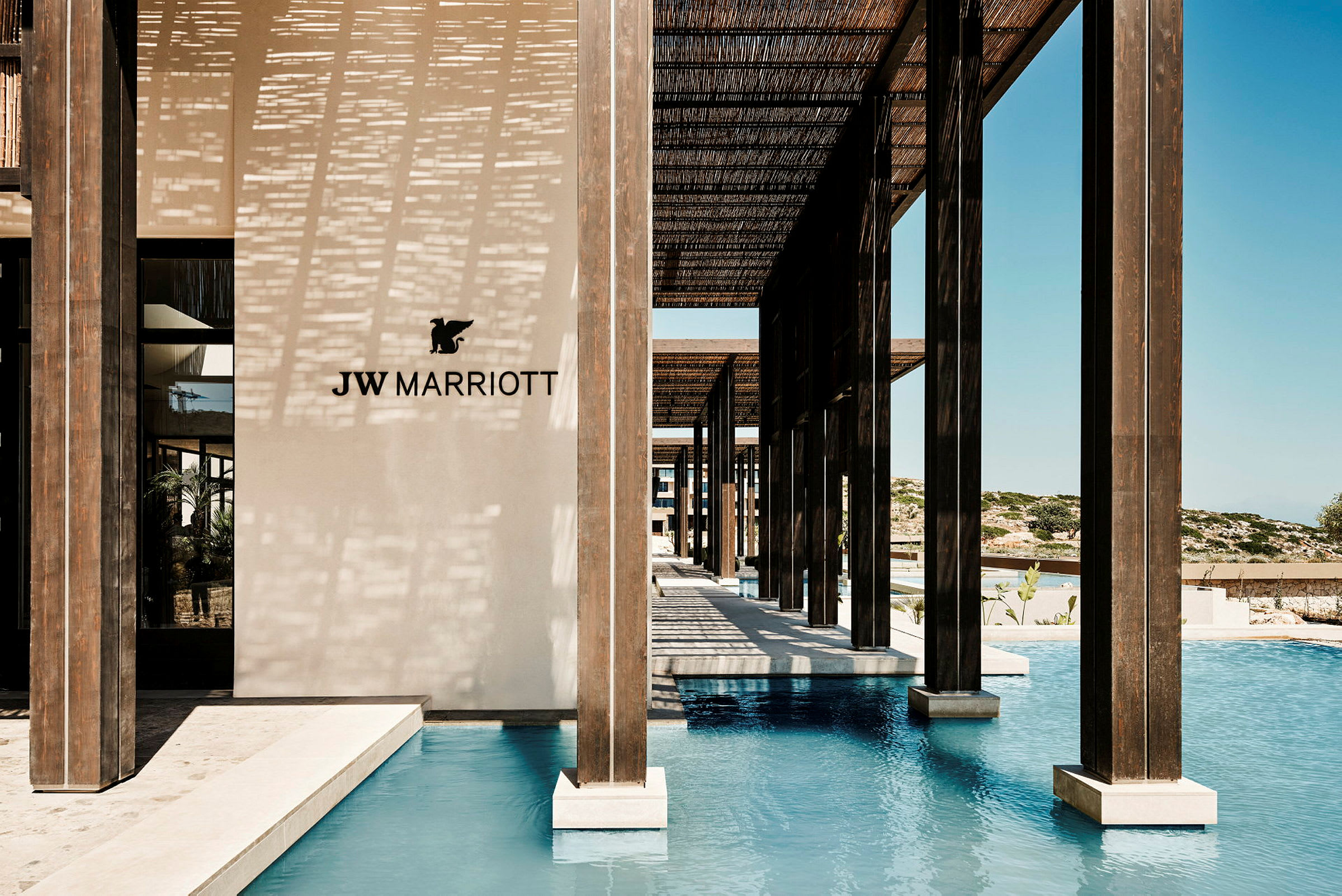 JW Marriott-logotyp på en ljus vägg vid en pool med träpelare. (AI-genererad text)