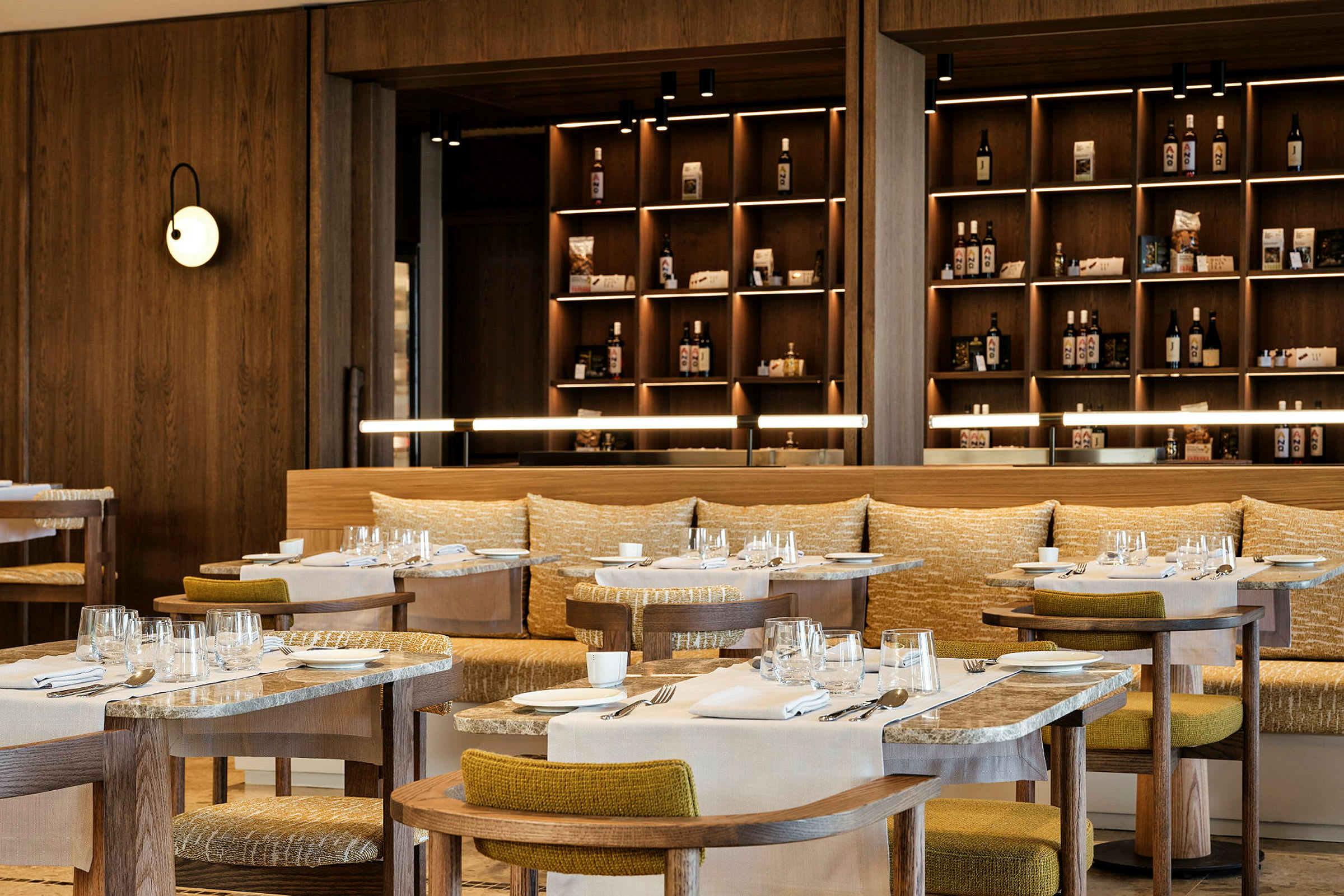 En restaurang med träinredning, dukade bord och hyllor med produkter i bakgrunden. (AI-genererad text)