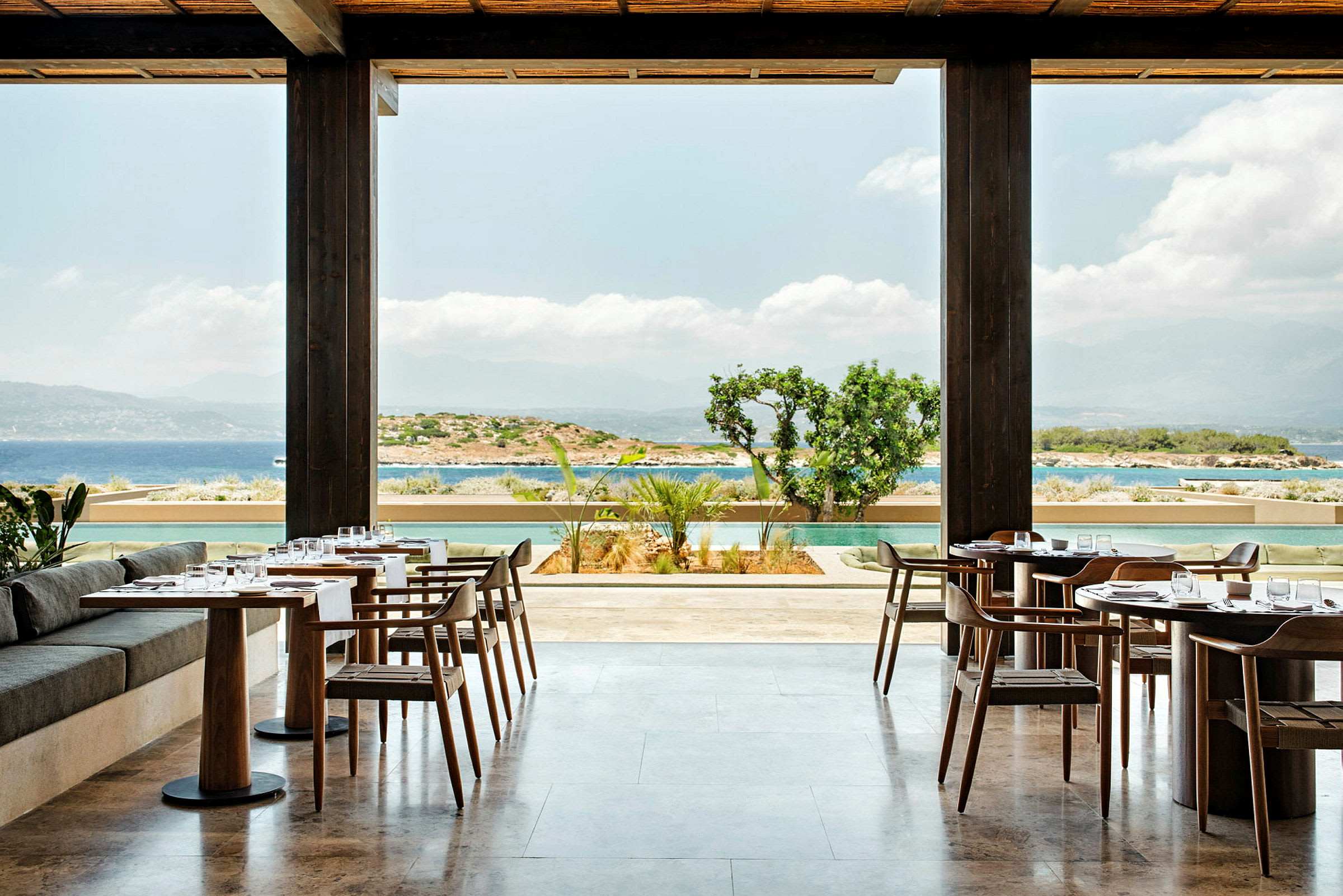 En restaurang med bord och stolar, med utsikt över havet och omgivningen. (AI-genererad text)