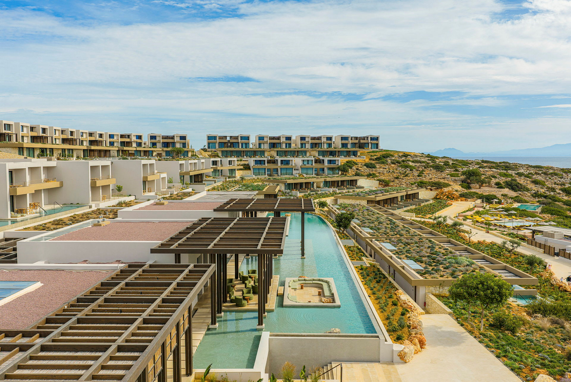 Bild av en modern hotellanläggning med flera byggnader, poolområden och terrasserade trädgårdar. (AI-genererad text)