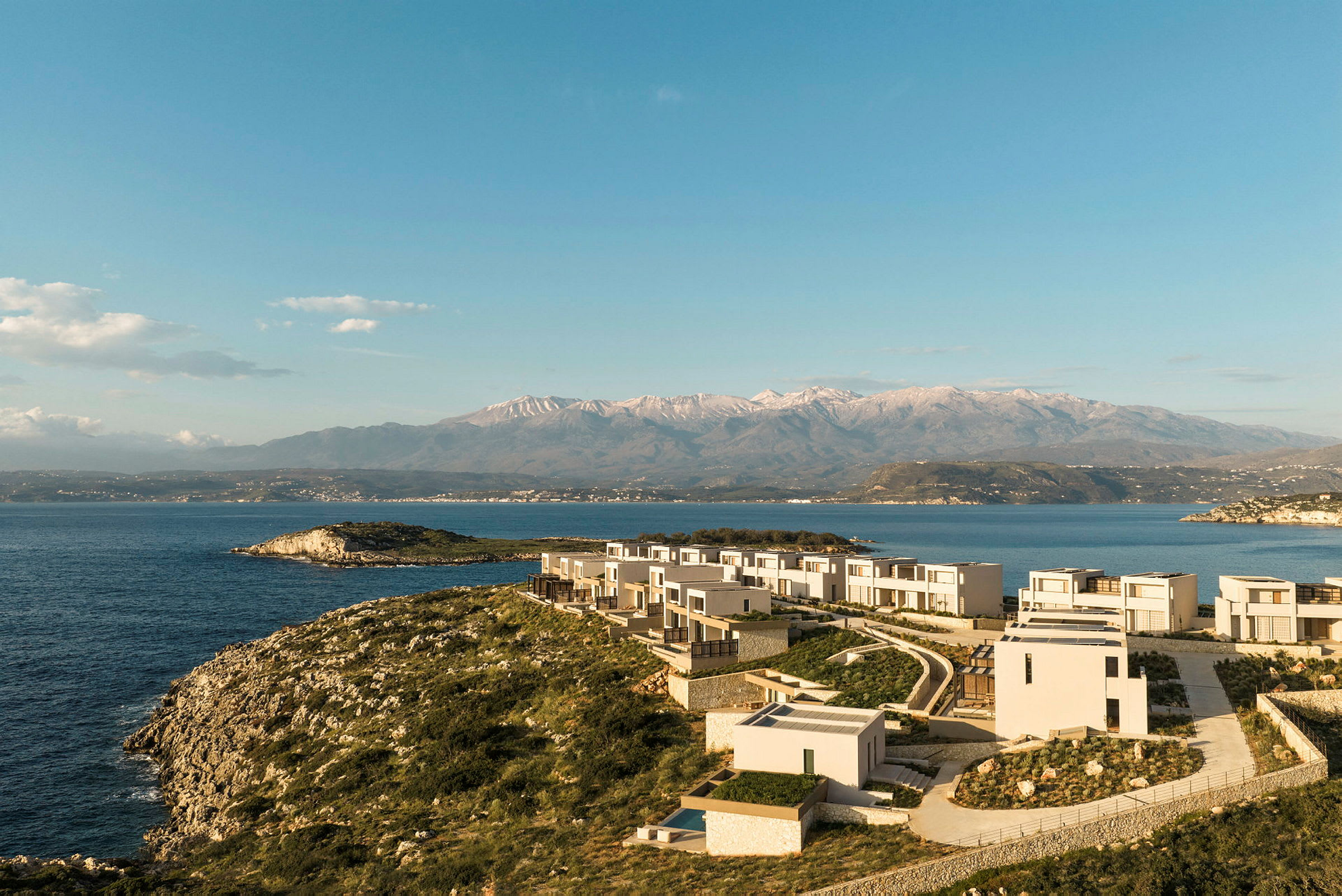 En kustlinje med modern arkitektur nära havet och berg i bakgrunden. (AI-genererad text)