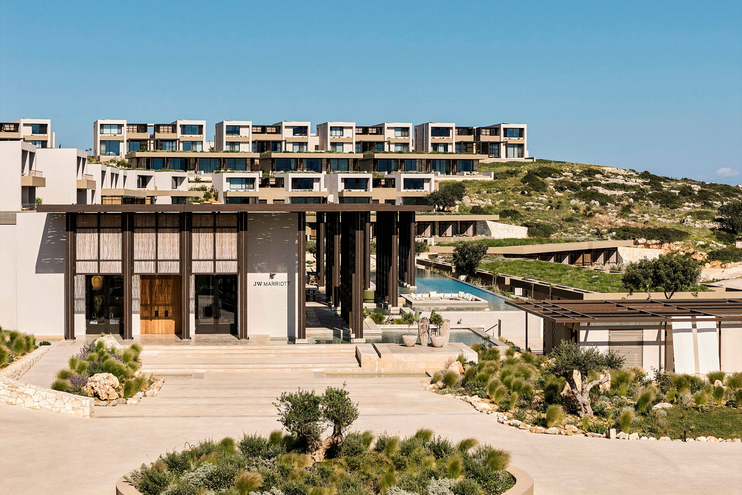 Bild av ett lyxigt hotellkomplex omgivet av grönska, med moderna byggnader och en pool. (AI-genererad text)