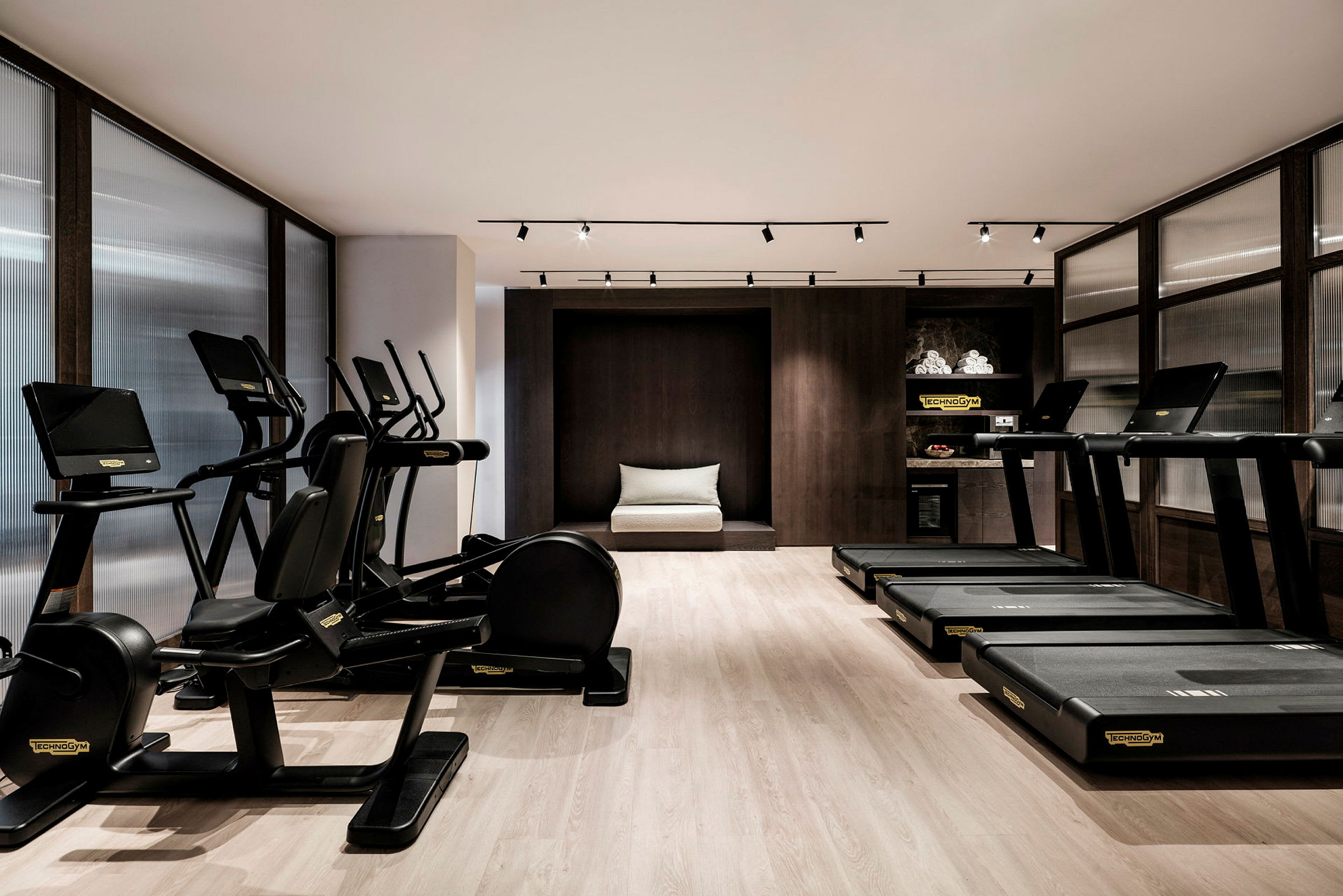 Ett modernt gym med träningsmaskiner och löpband placerade i ett elegant inrett rum. (AI-genererad text)