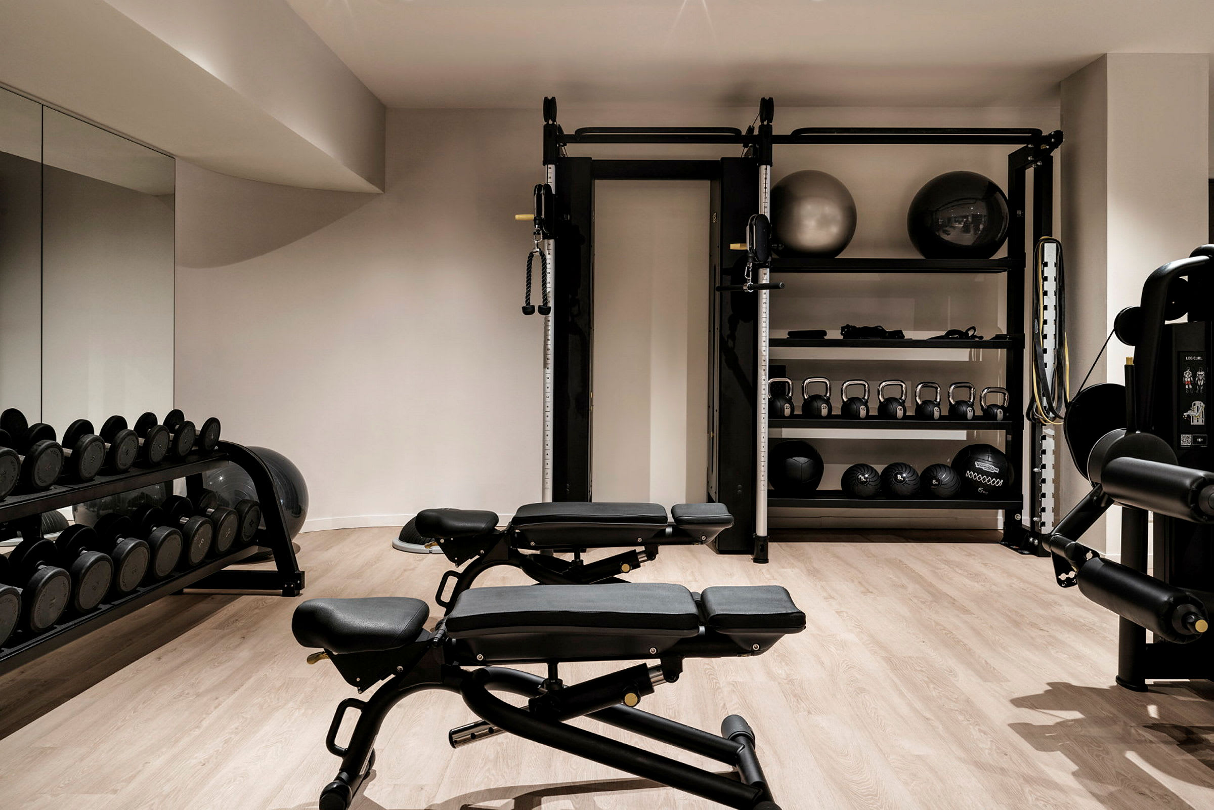 Ett gym med utrustning såsom bänkar, fria vikter och pilatesbollar. (AI-genererad text)