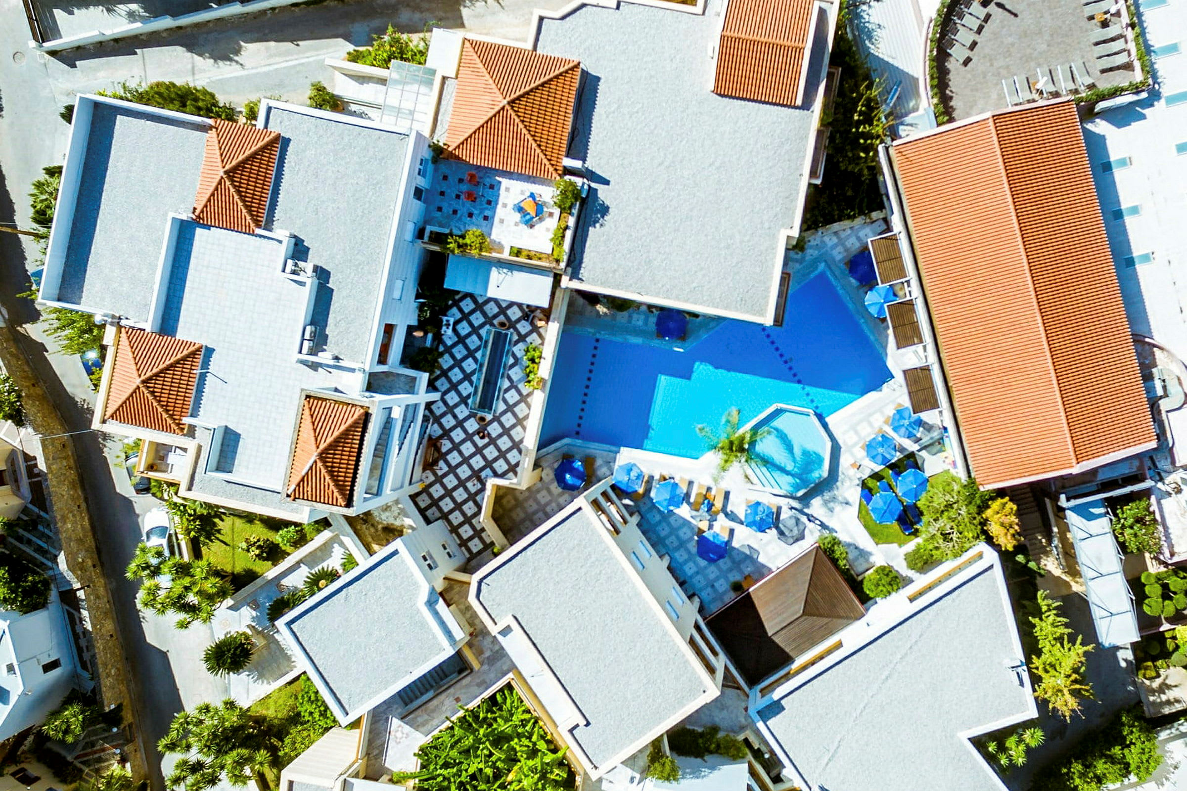 Flygbild över hotellområde med byggnader och en pool. (AI-genererad text)