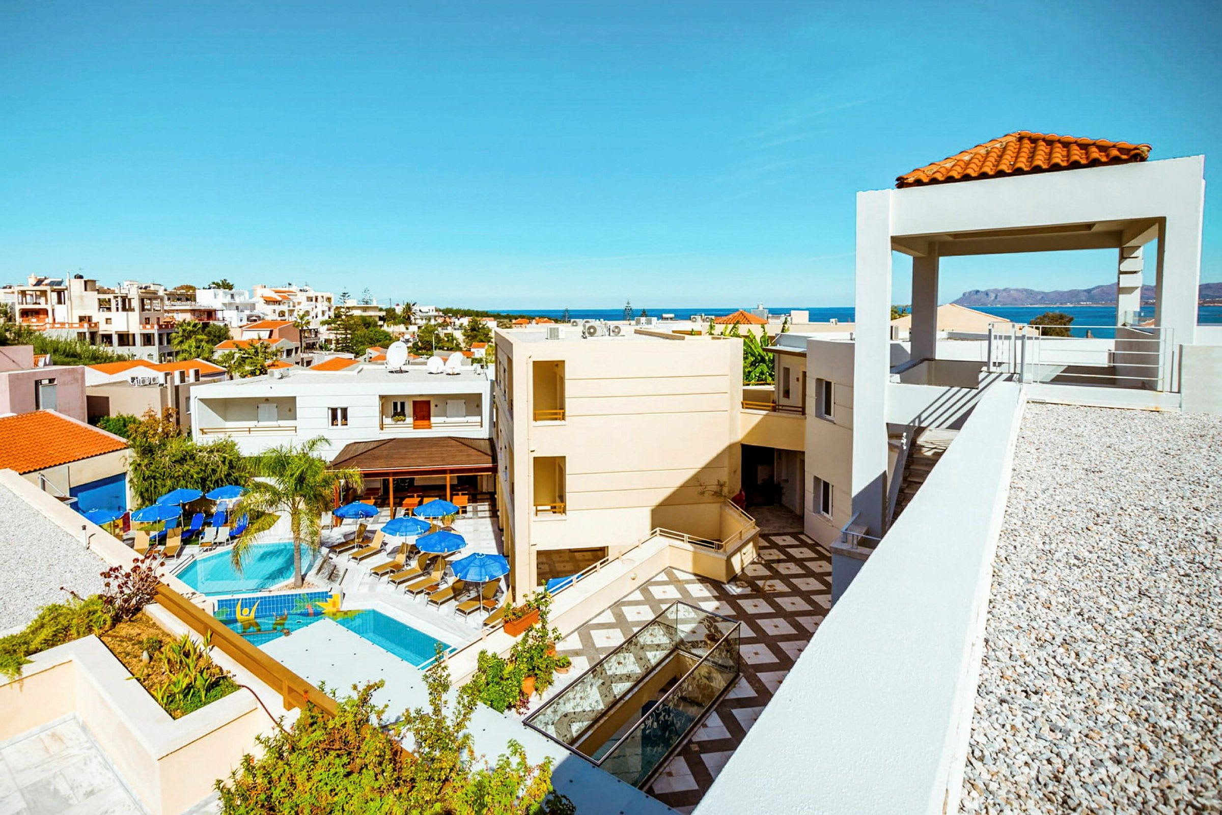 Hotellanläggning med pool, solstolar och havsutsikt i bakgrunden. (AI-genererad text)