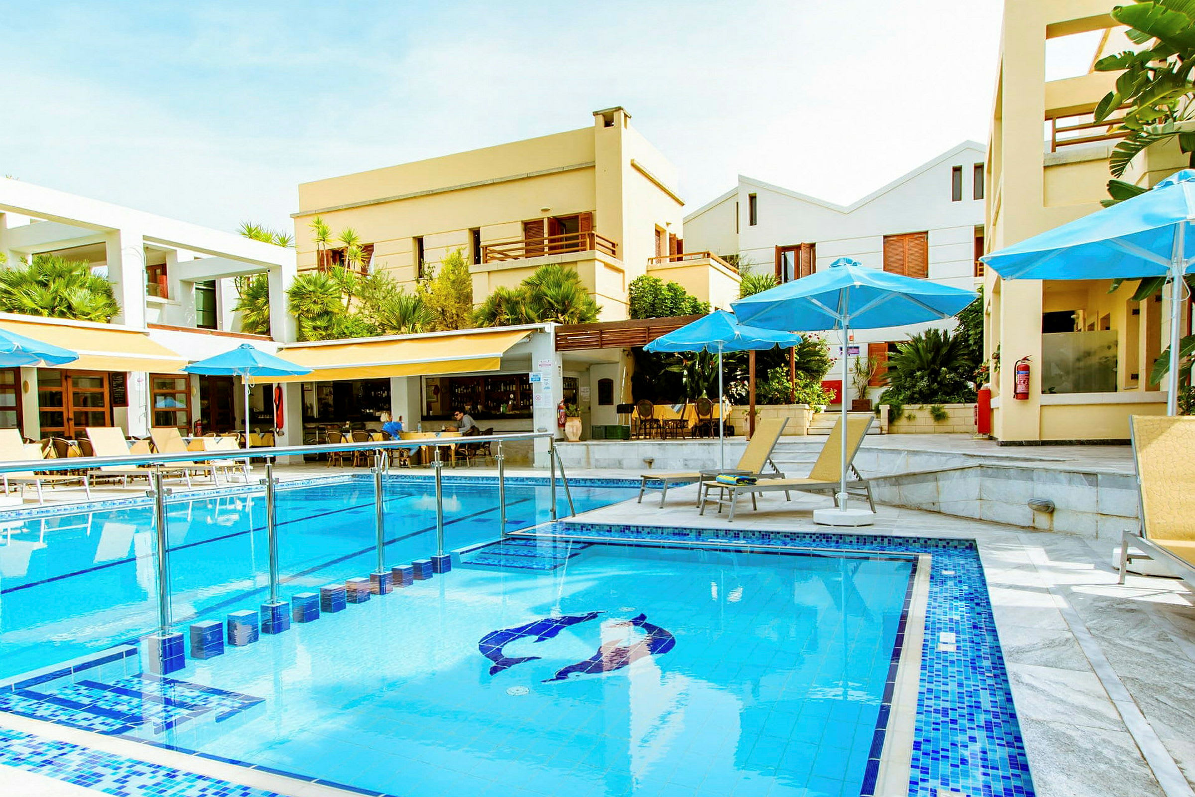 Hotellpool med blått vatten omgiven av solstolar och parasoller. (AI-genererad text)