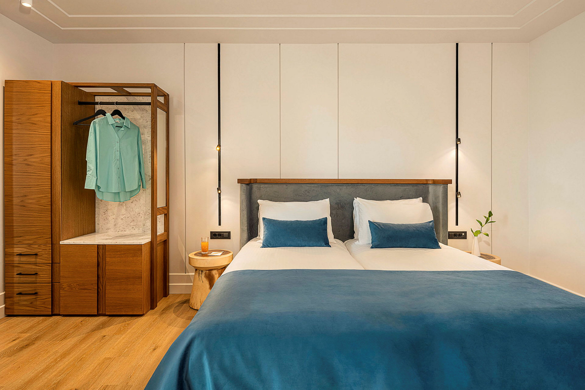 Två enkelsängar med blå överkast och kuddar i ett modernt hotellrum. (AI-genererad text)