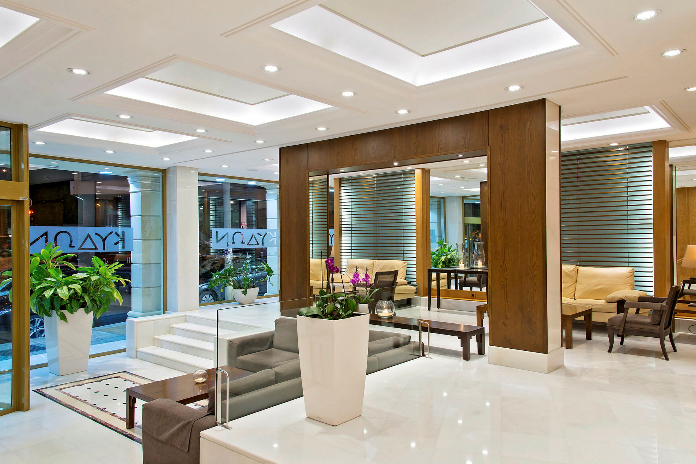 Hotellobby med modern inredning, vita golv, soffor och gröna växter. (AI-genererad text)