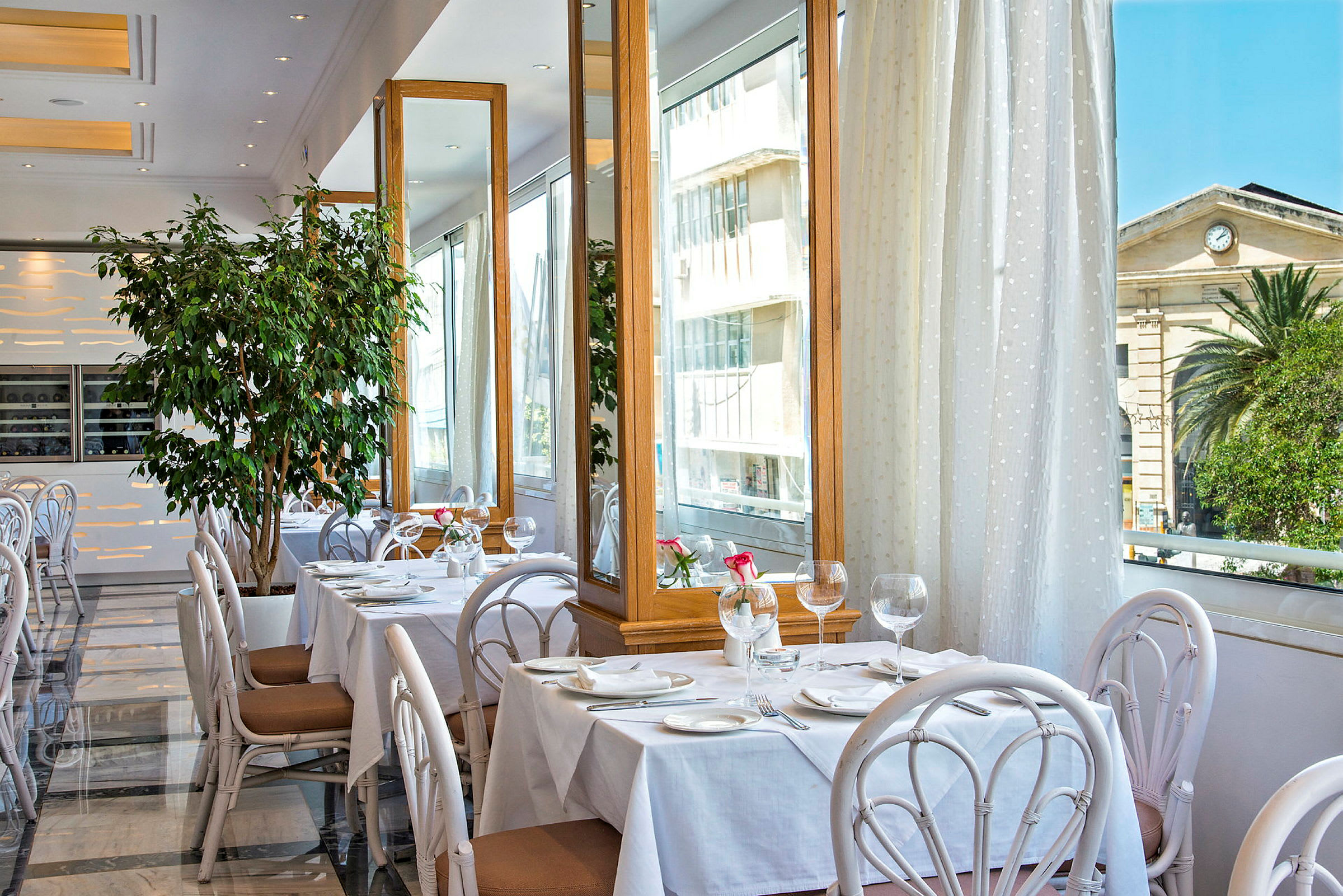 En restaurang med dukade bord, stora speglar och grön inredning. (AI-genererad text)