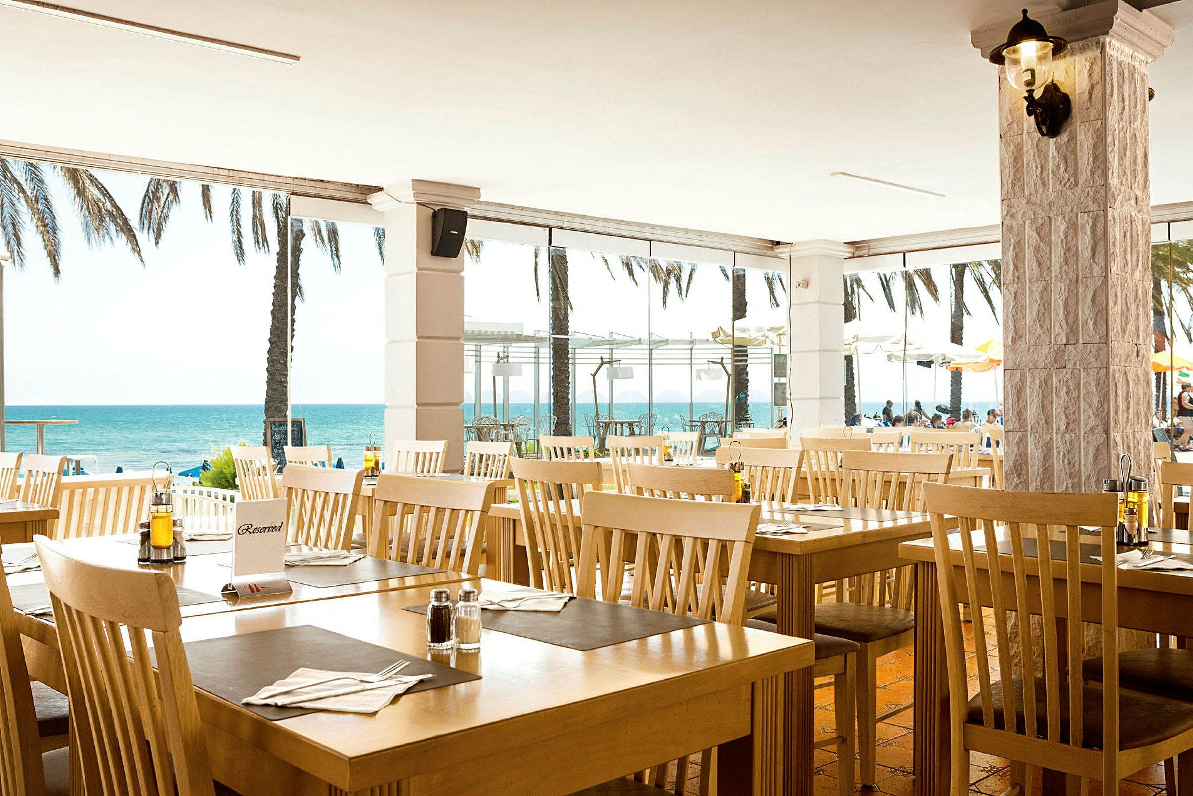 Restaurang med träbord och stolar vid stranden. (AI-genererad text)