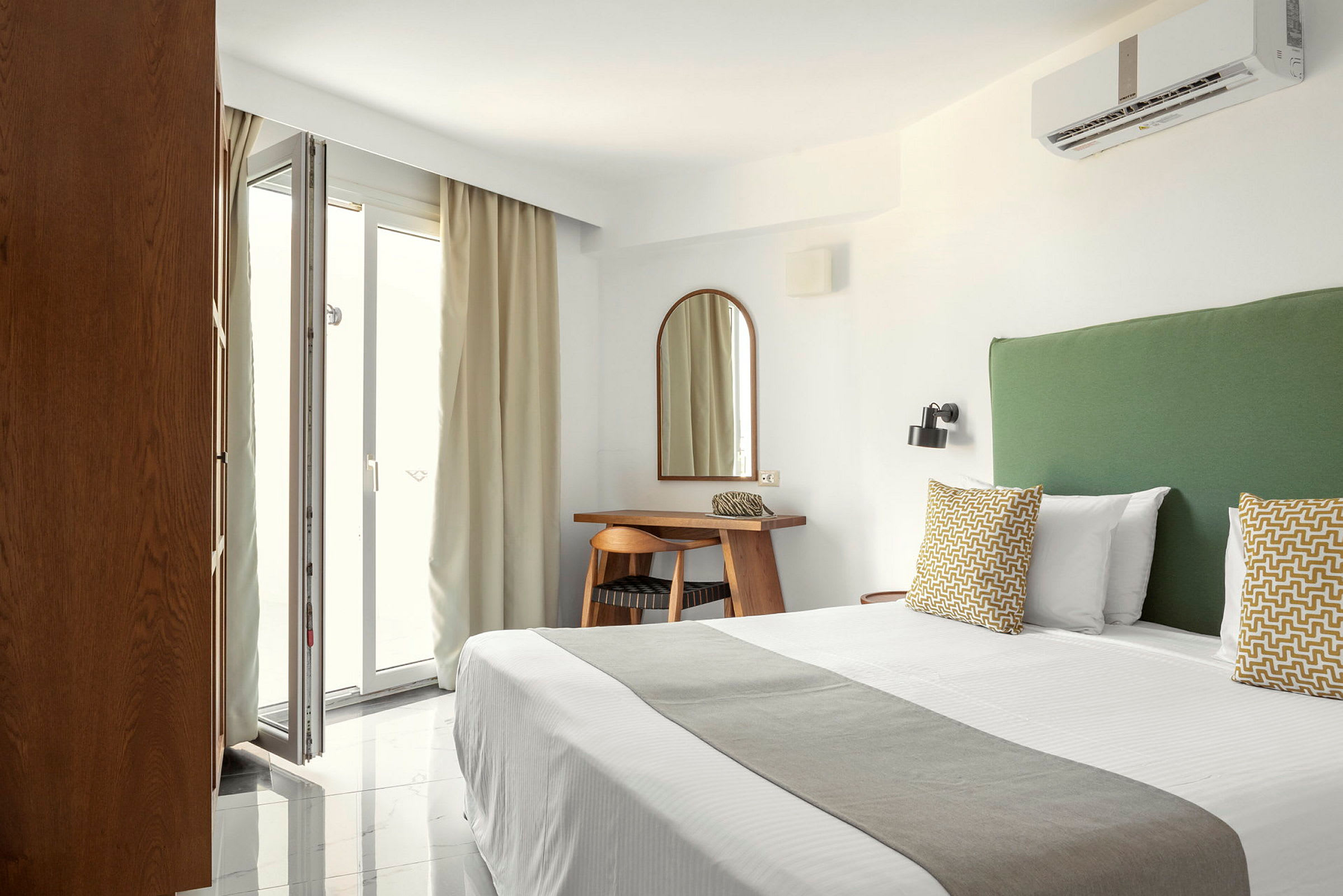 Hotellrum med säng, grön sänggavel och skrivbord vid en spegel. (AI-genererad text)