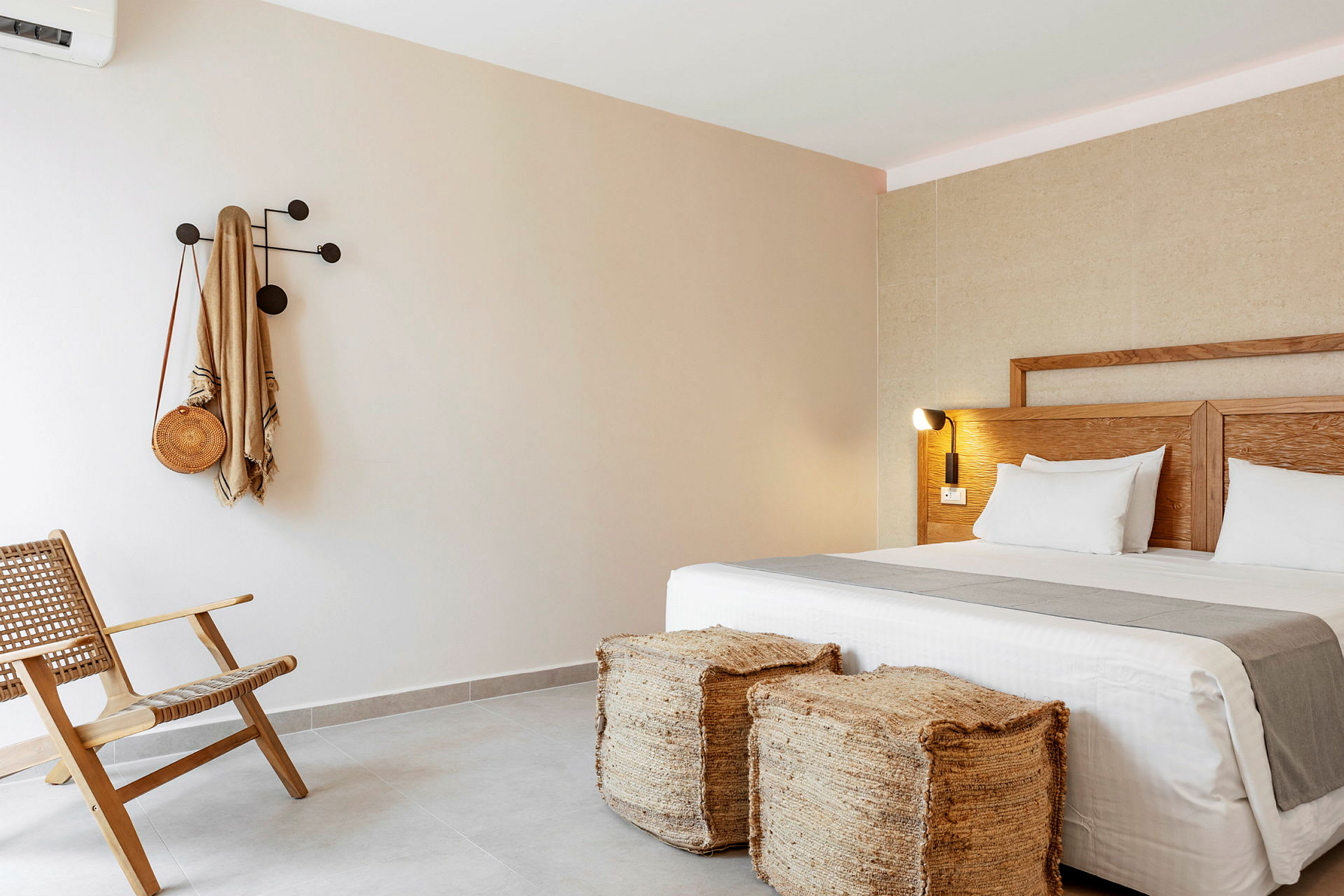 Hotellrum med en modern inredning, inklusive en säng, två avföringspallar, en stol och en krok på väggen. (AI-genererad text)