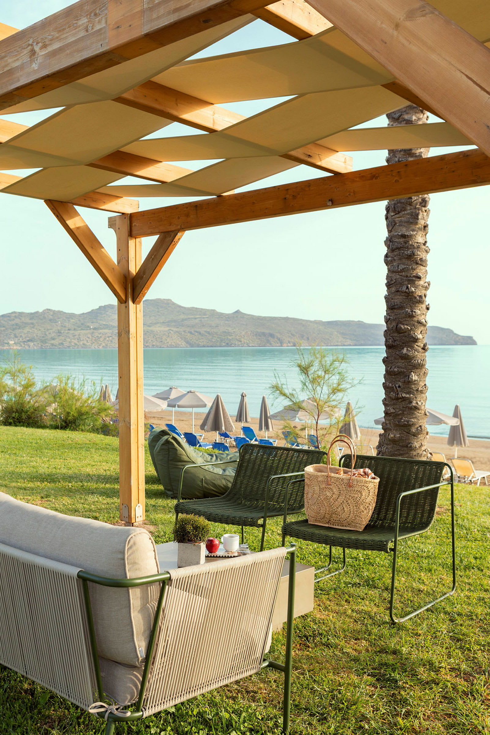 Trädgårdmöbler under en träpergola med utsikt över stranden och havet. (AI-genererad text)