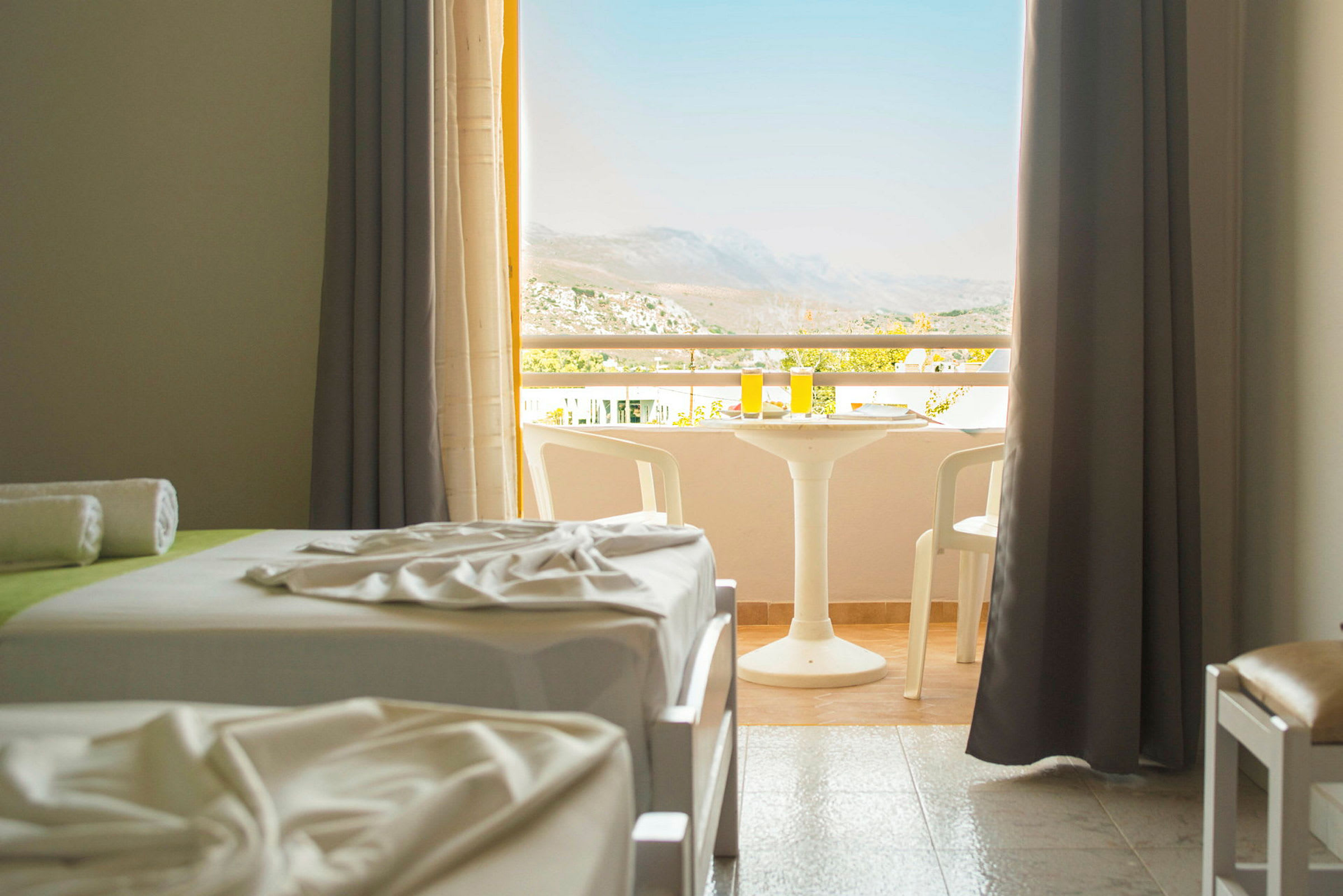 Ett hotellrum med två bäddar och en möblerad balkong med utsikt. (AI-genererad text)