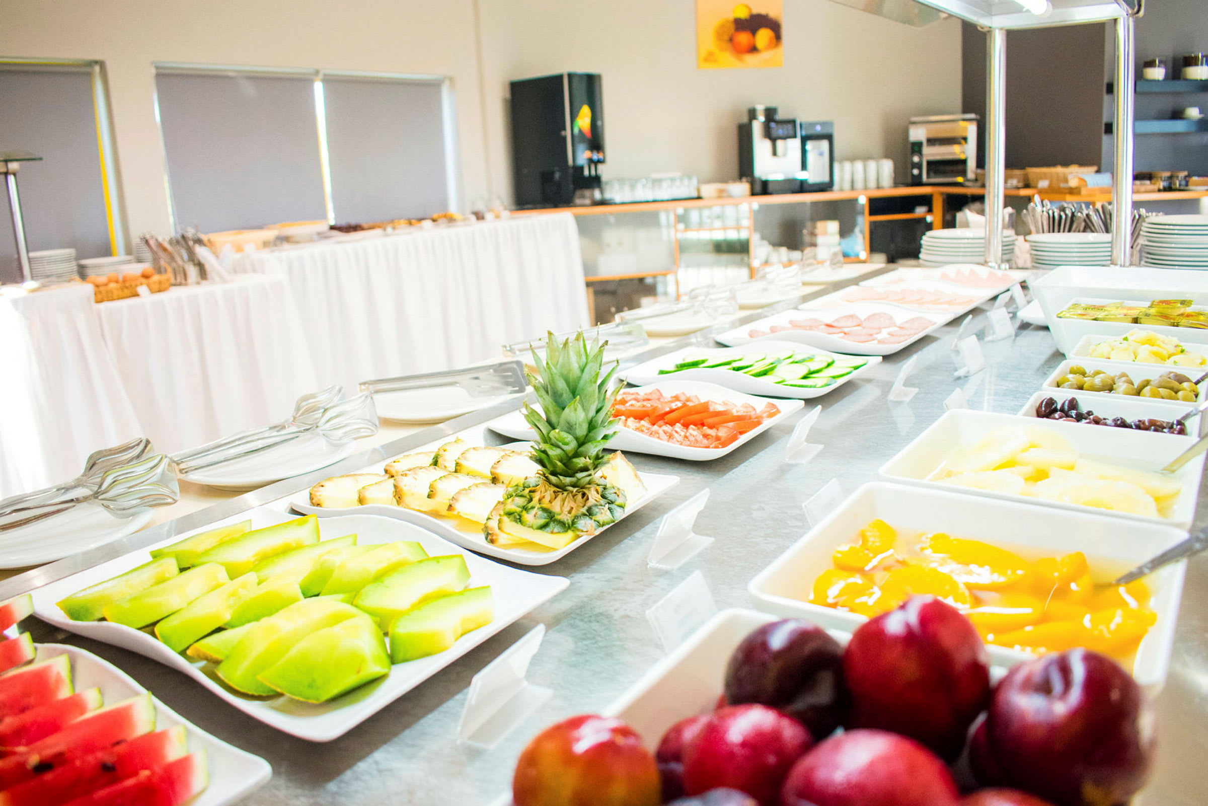 Ett buffébord med olika maträtter, inklusive frukt, grönsaker och andra livsmedel, presenteras i vita serveringsfat. (AI-genererad text)