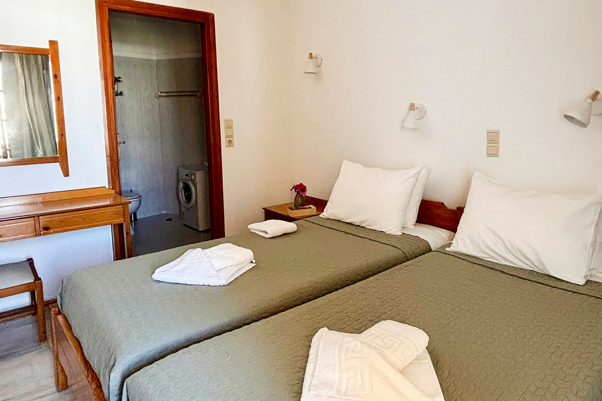 Ett hotellrum med två enkelsängar, badrummet inkluderar en tvättmaskin. (AI-genererad text)