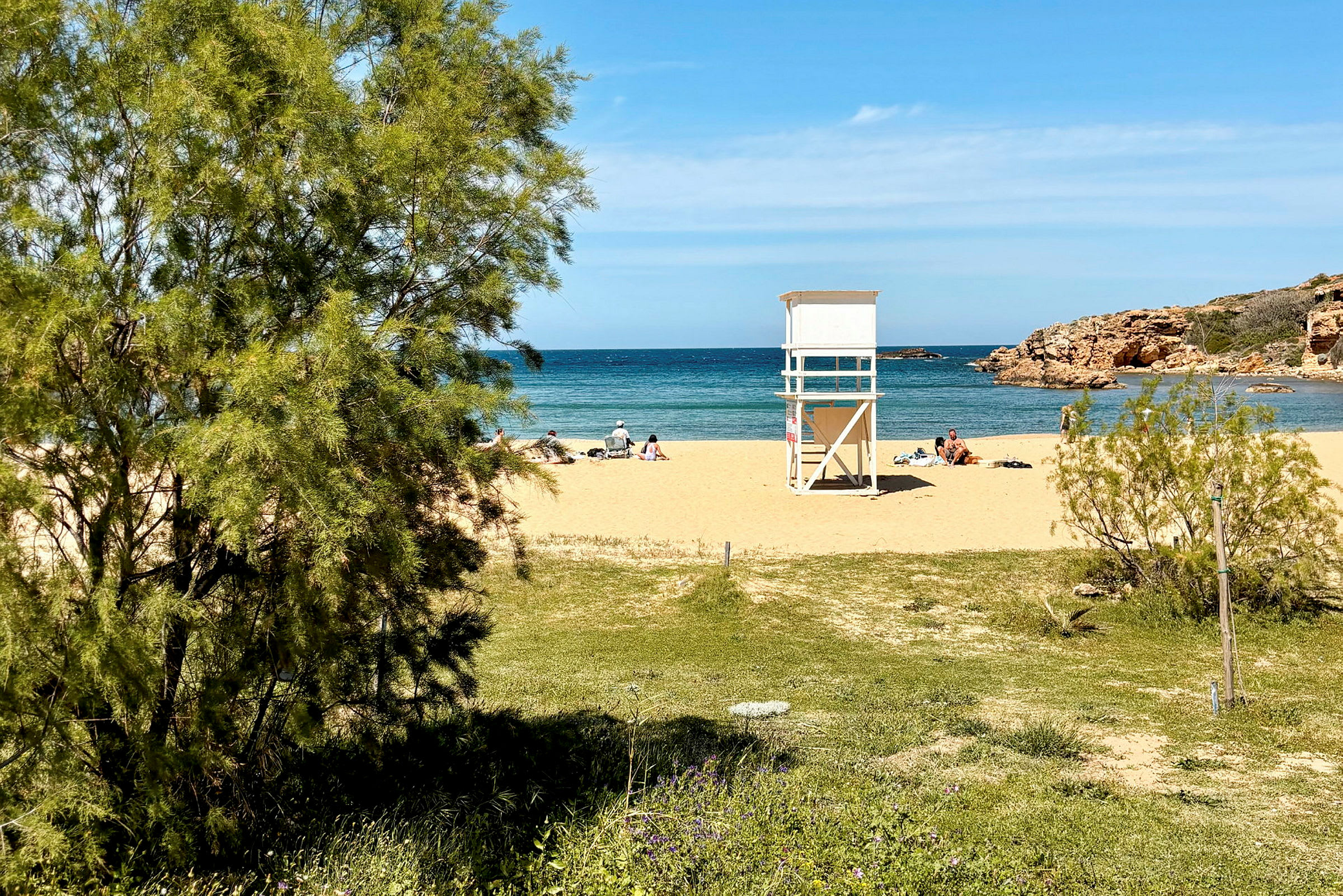 En sandstrand med badgäster, en livräddartorn och utsikt mot havet. (AI-genererad text)