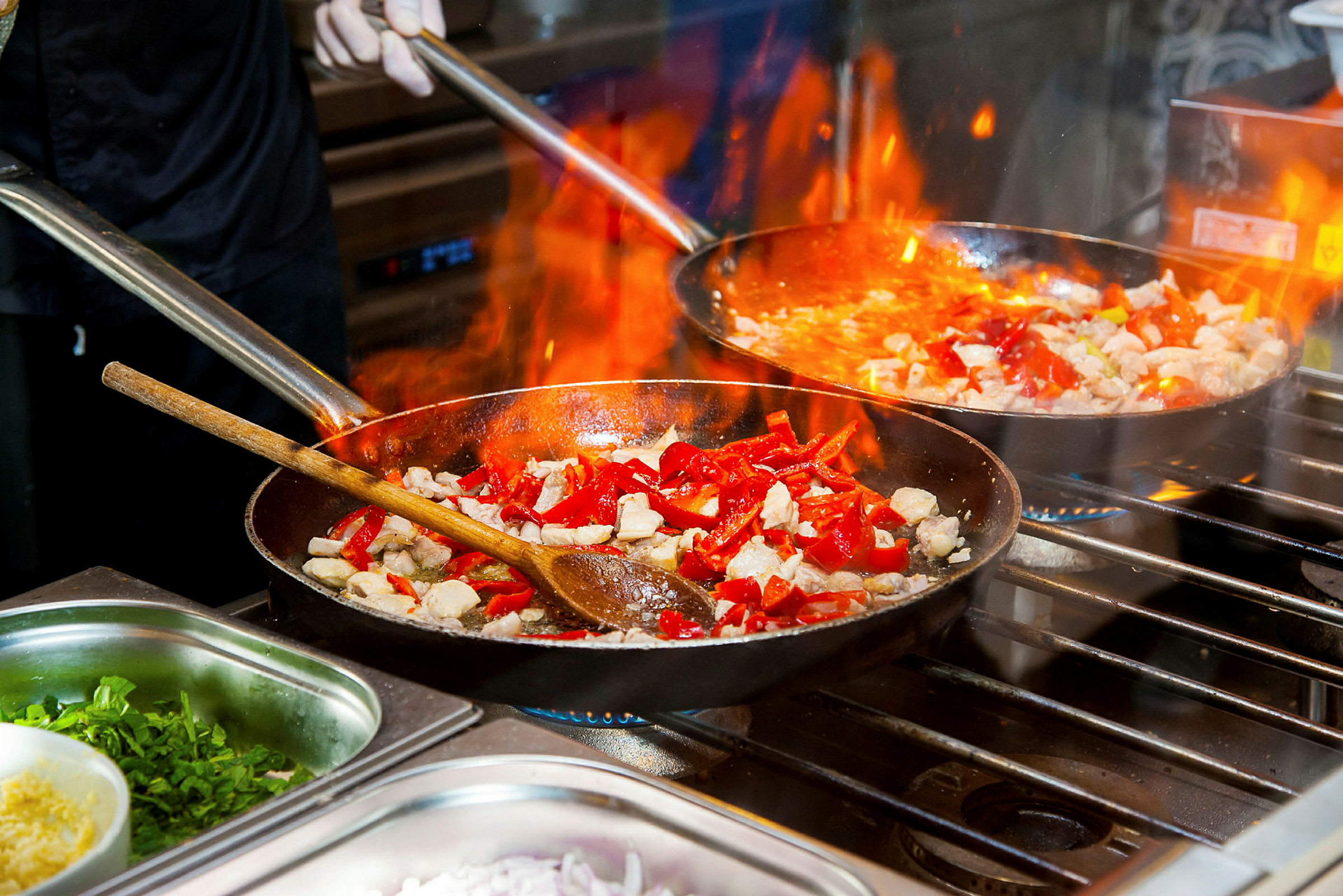 Matlagning i stekpannor med eldflamma, inklusive röda paprikor och kyckling. (AI-genererad text)