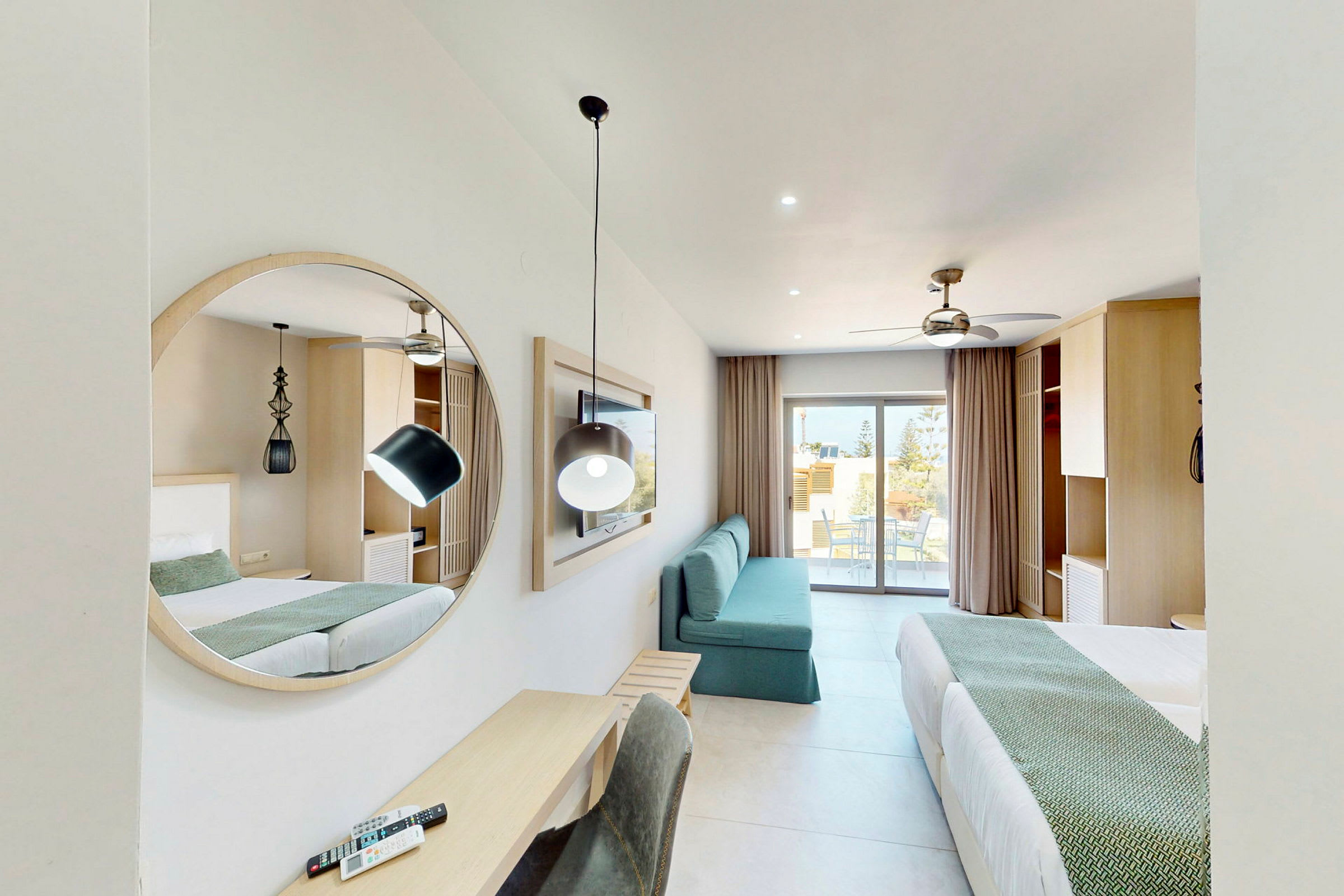 Ett modernt hotellrum med två sängar, en spegel, en soffa och ett skrivbord. En balkong syns i bakgrunden. (AI-genererad text)