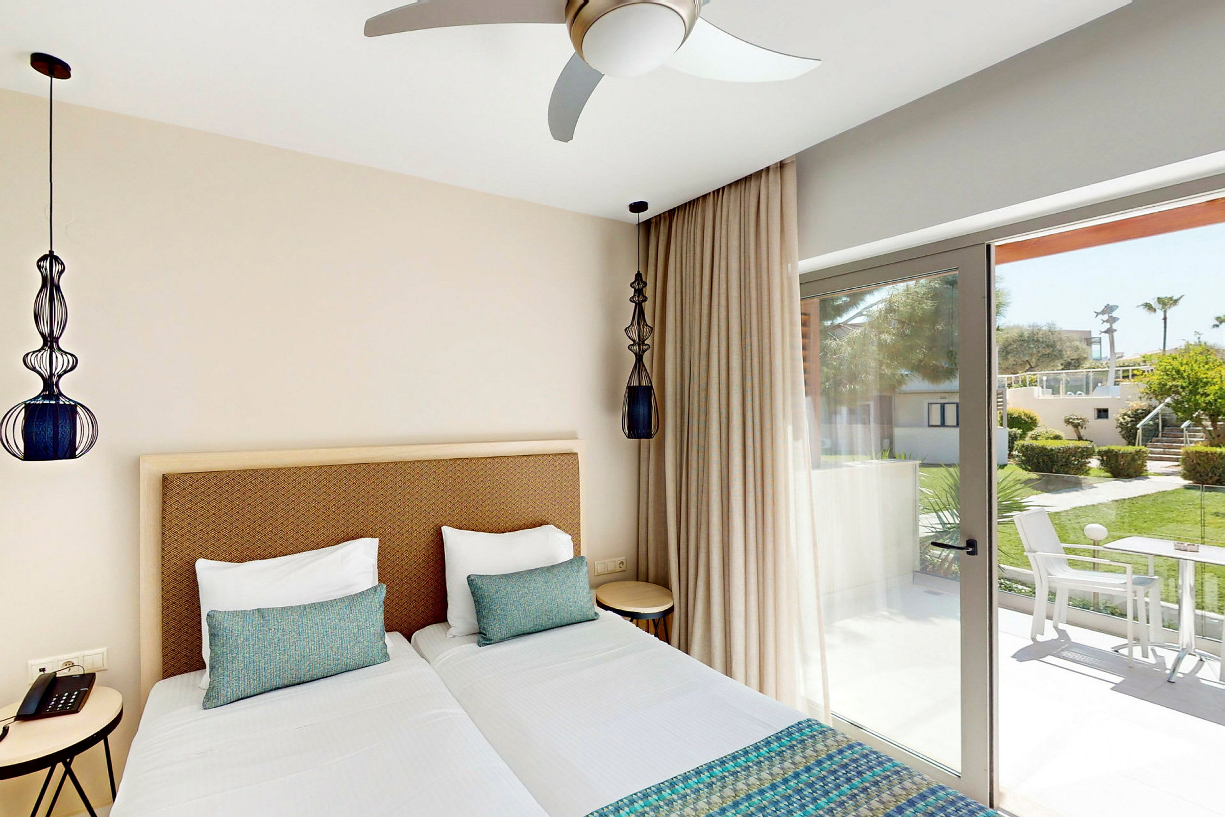 Ett hotellrum med två enkelsängar och fönster som vetter mot en grönskande trädgård. (AI-genererad text)