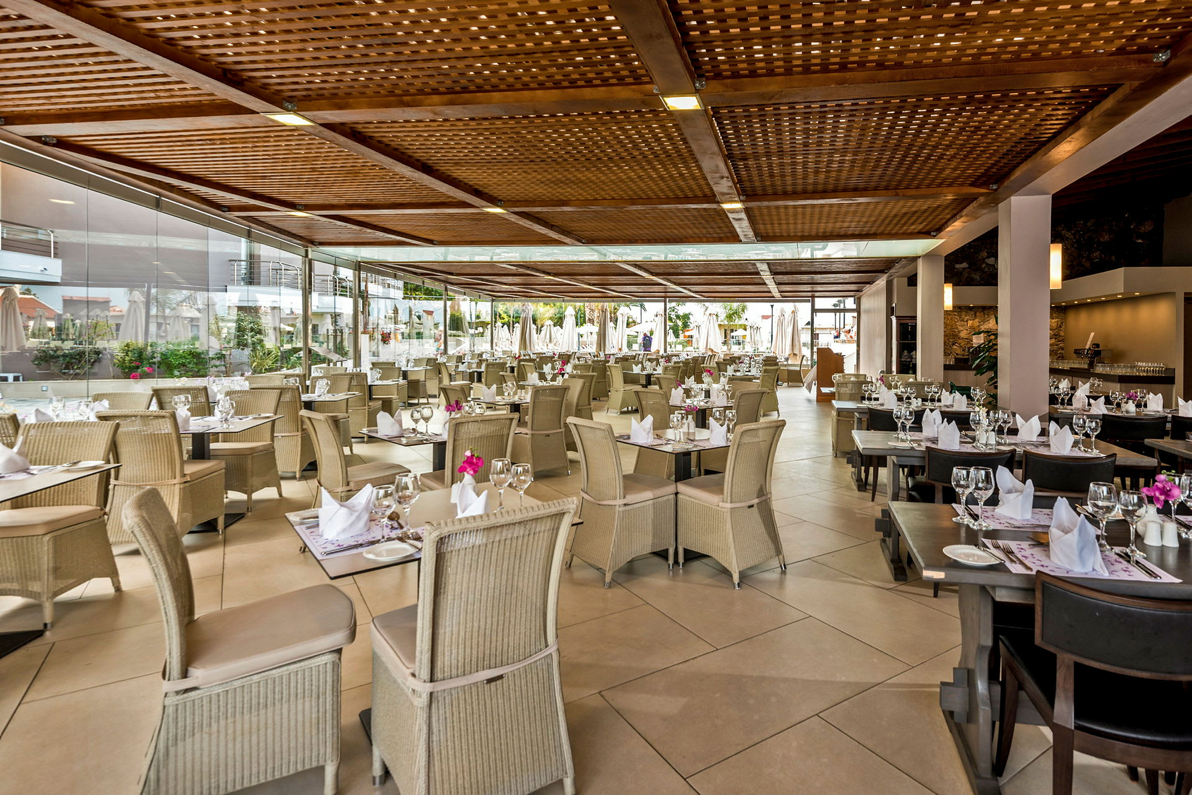 Restaurang med dukade bord och stolar under en träpergola. (AI-genererad text)