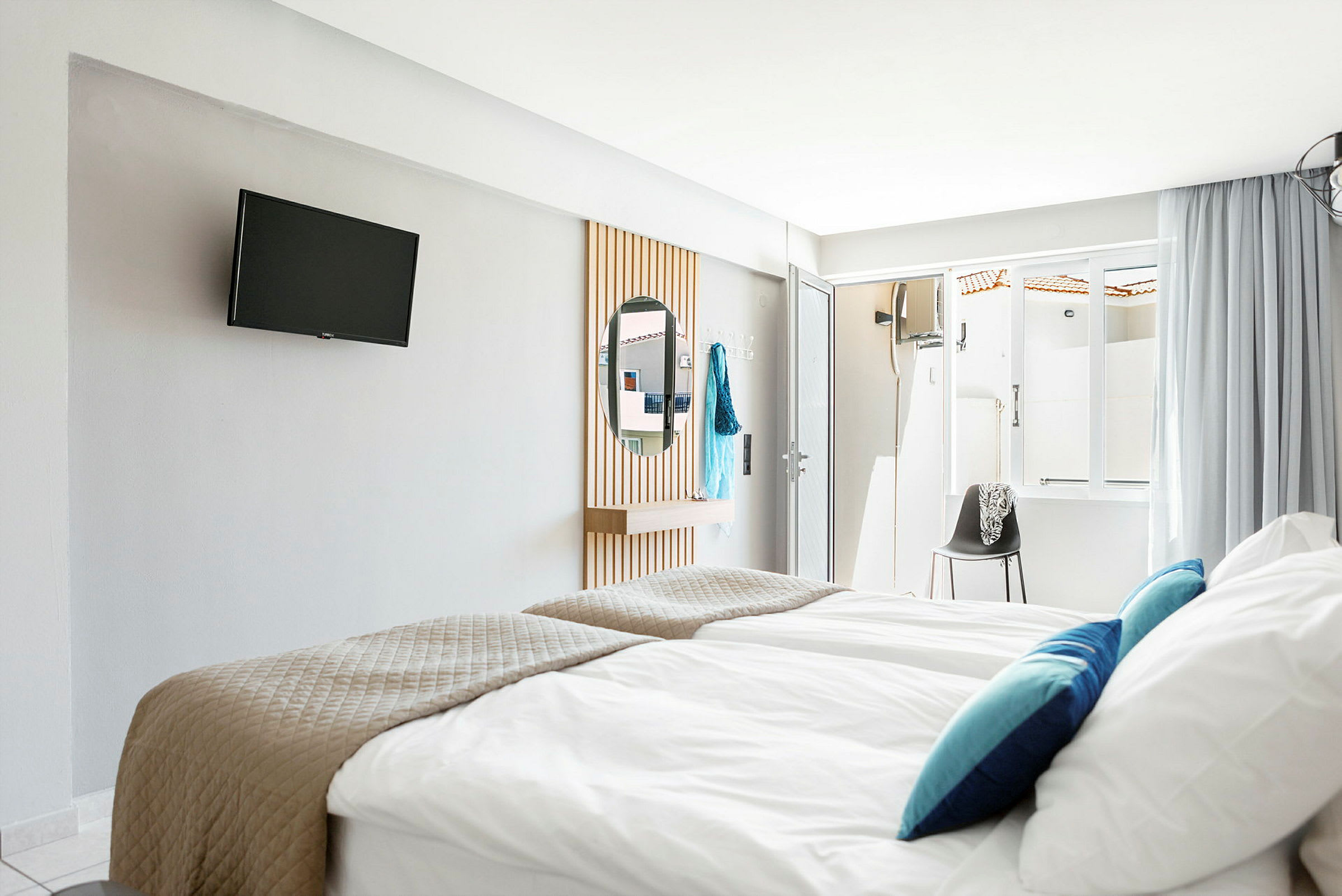 Hotellrum med sängar, TV på väggen, och en spegel. (AI-genererad text)
