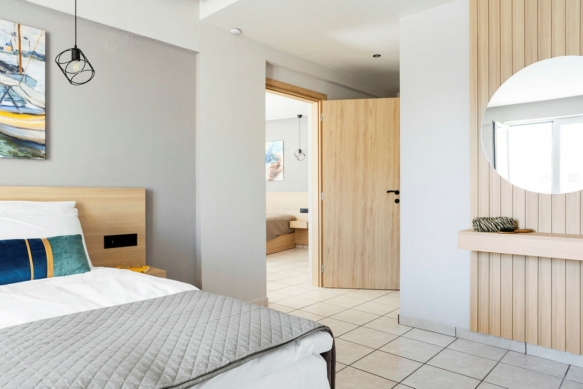 Interiören i ett hotellrum med en säng, en spegel och en öppen dörr. (AI-genererad text)