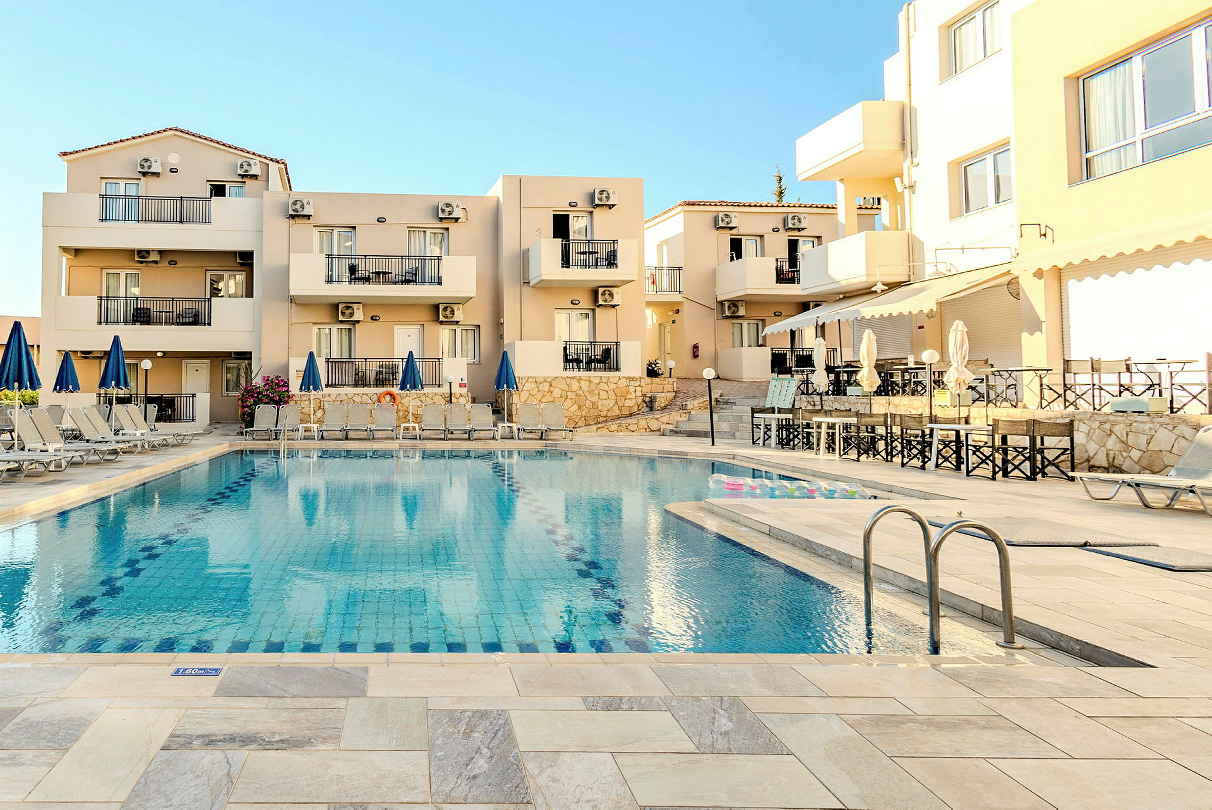 Hotellområde vid en pool med stolar och parasoller. (AI-genererad text)