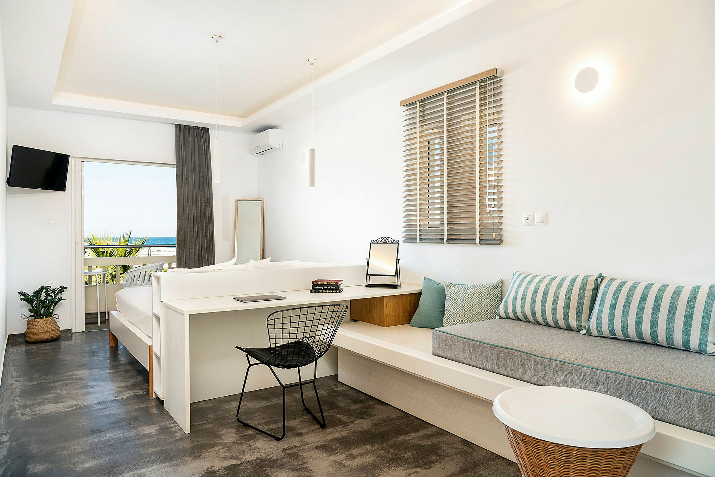 Hotellrum med ljus inredning och utsikt över havet från en balkong. (AI-genererad text)