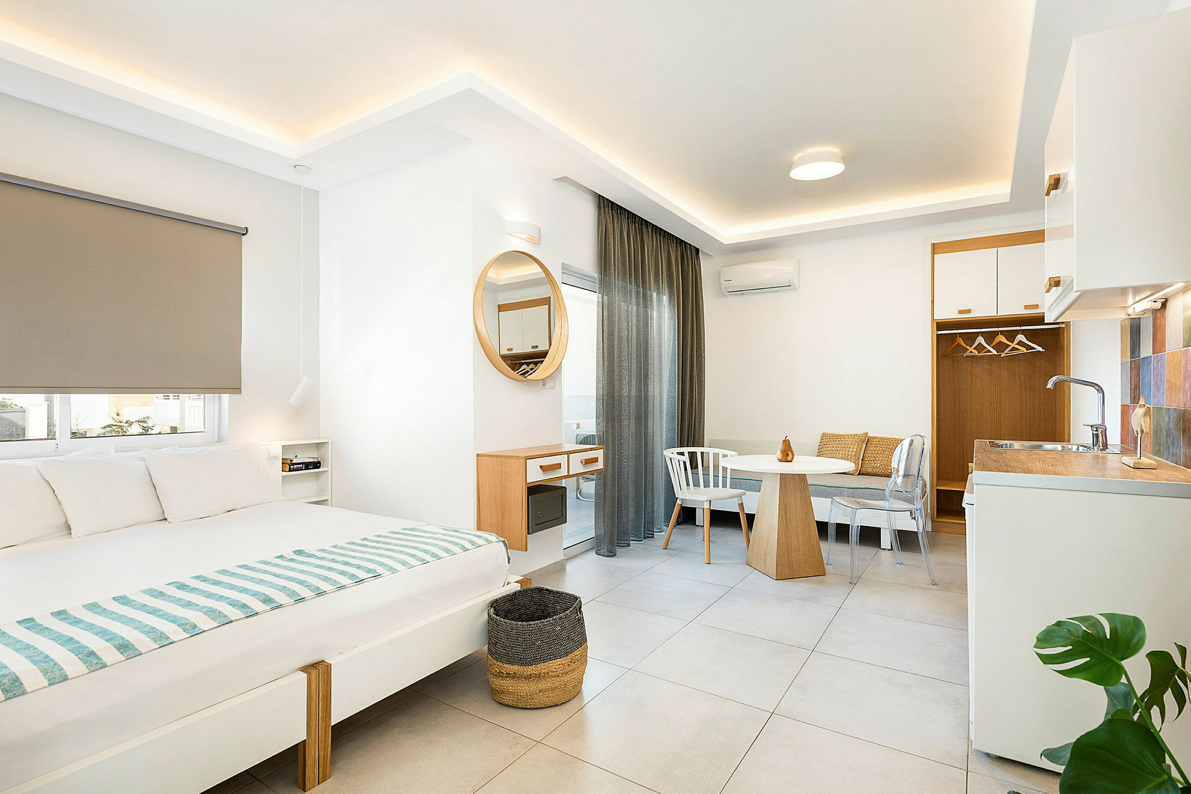 Interiör av ett modernt hotellrum med säng, matbord och liten köksdel. (AI-genererad text)