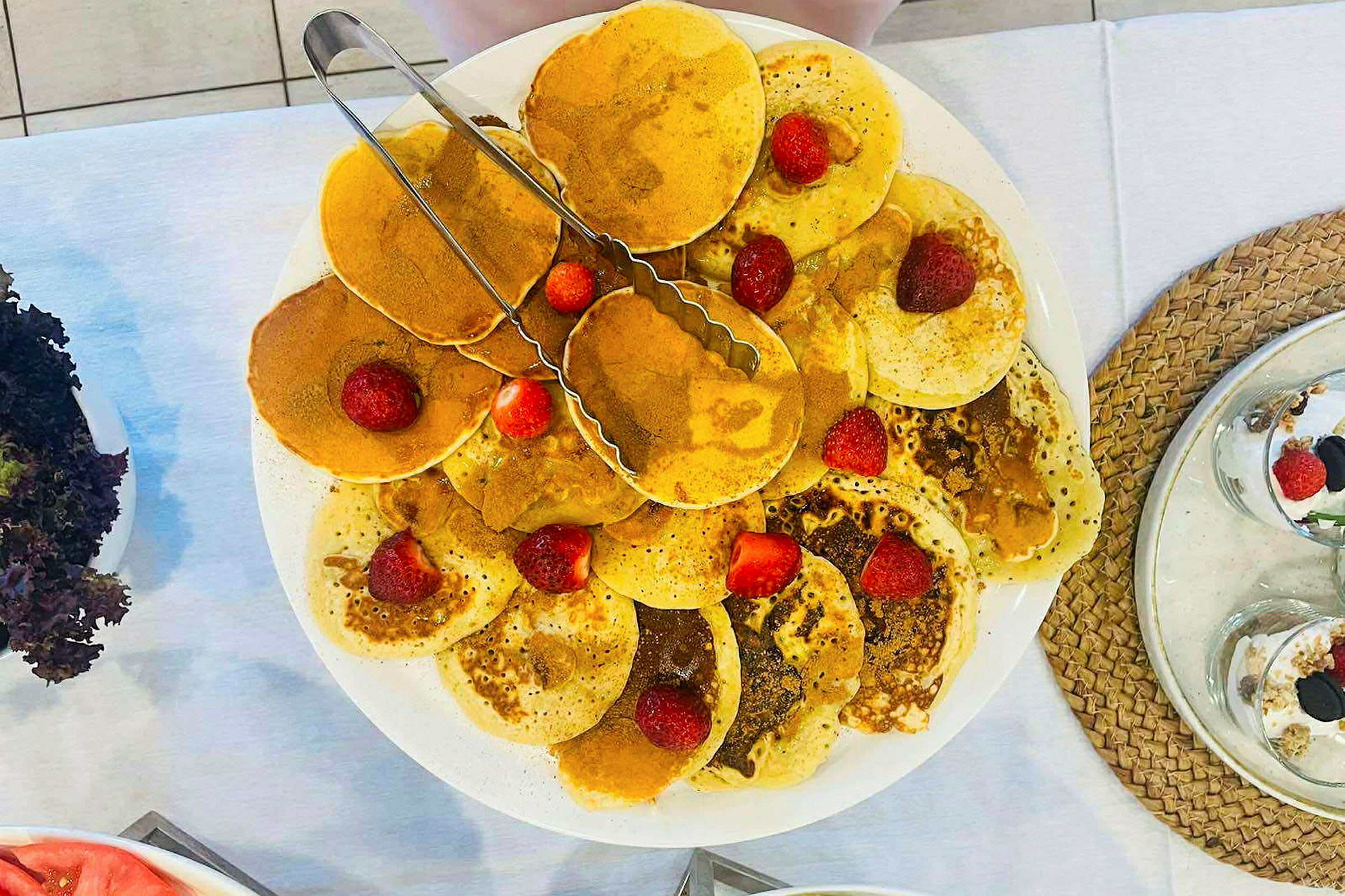 En tallrik med pannkakor dekorerade med färska jordgubbar. (AI-genererad text)