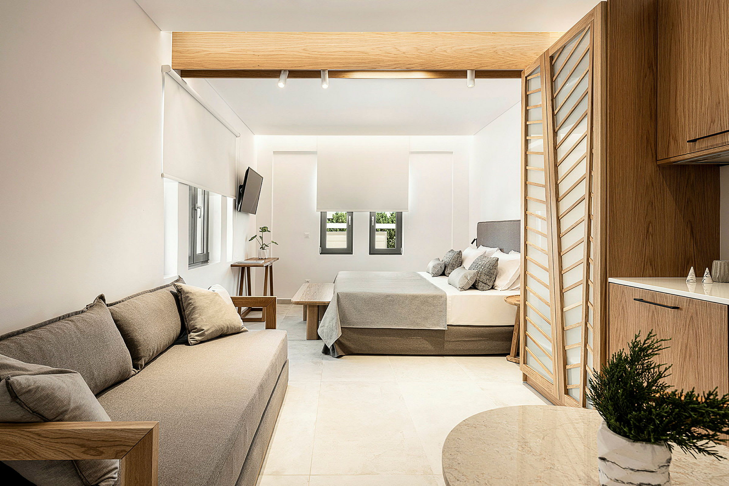 Modernt inredd hotellsvit med sittmöbler, säng och köksavdelning. (AI-genererad text)