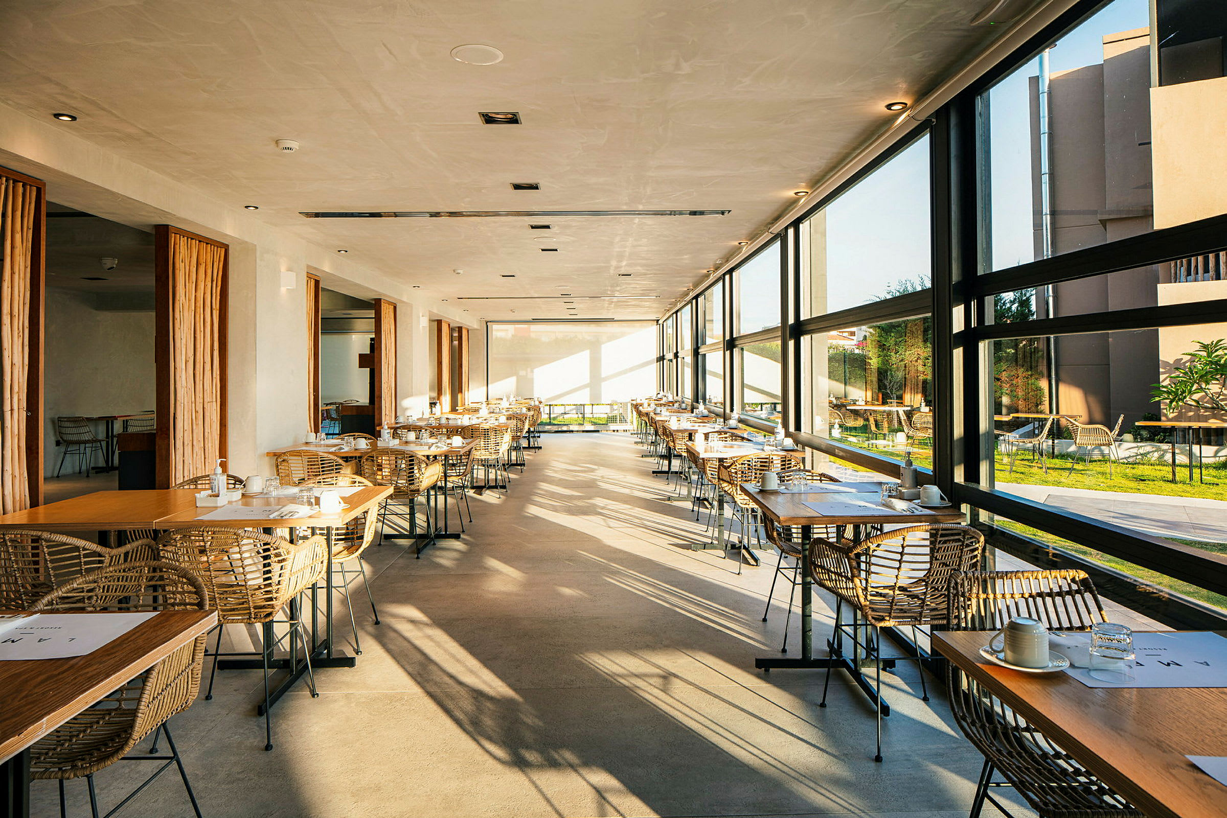 Restaurang med stora fönster och dukade bord. (AI-genererad text)