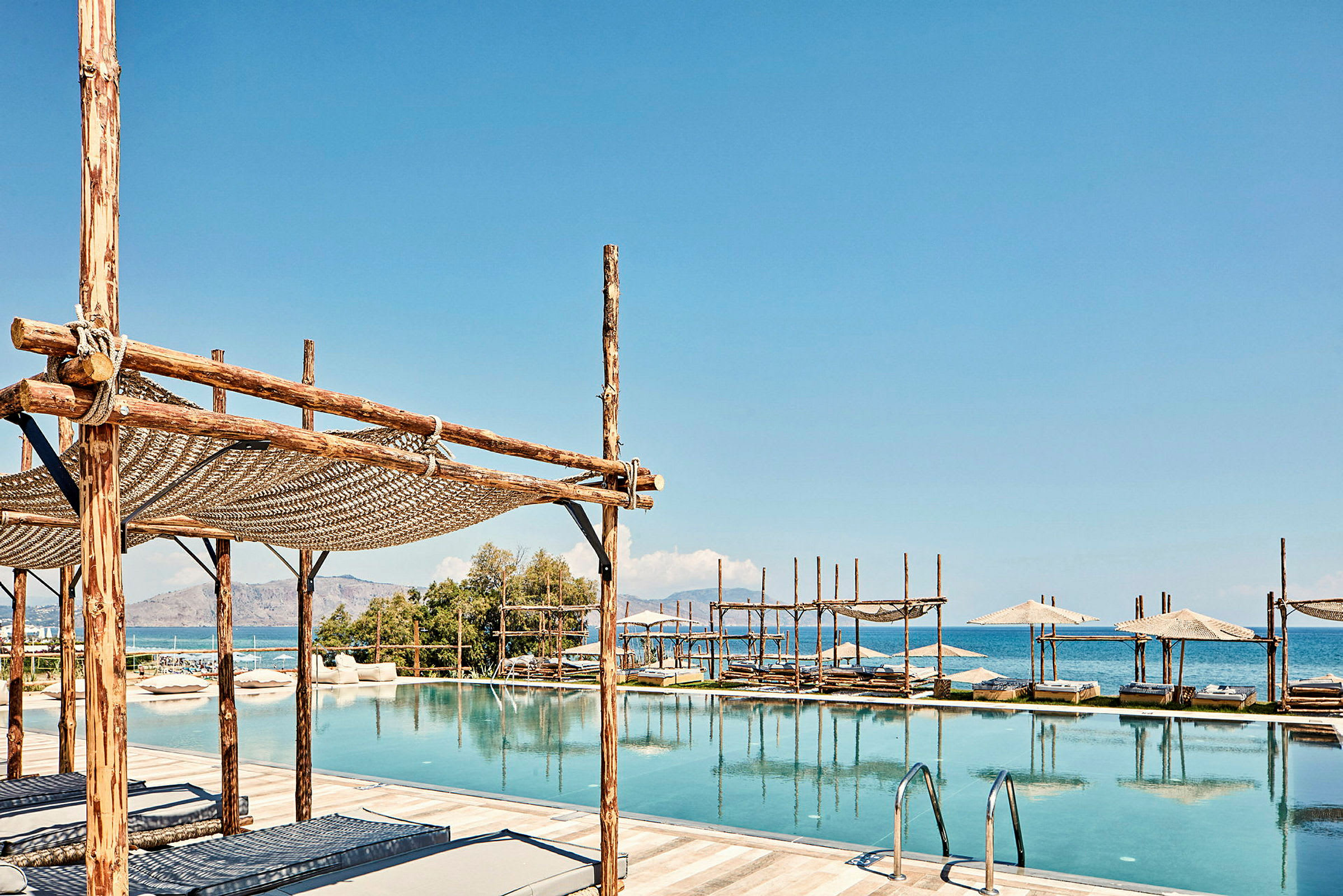 Pool med solstolar och parasoller vid kusten. (AI-genererad text)