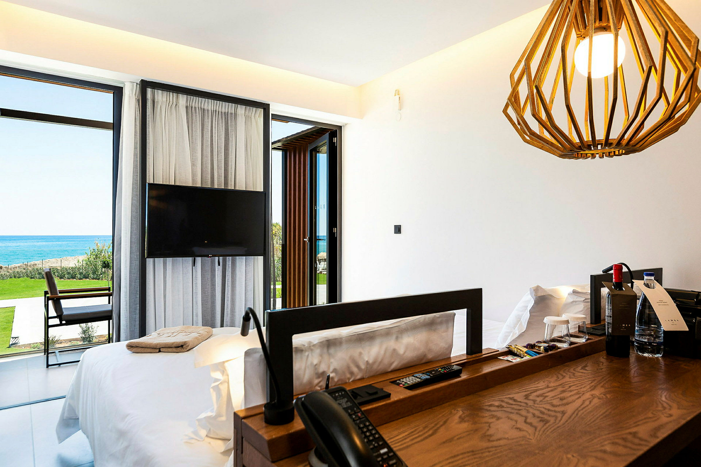 Hotellrum med säng, TV och utsikt över havet. (AI-genererad text)