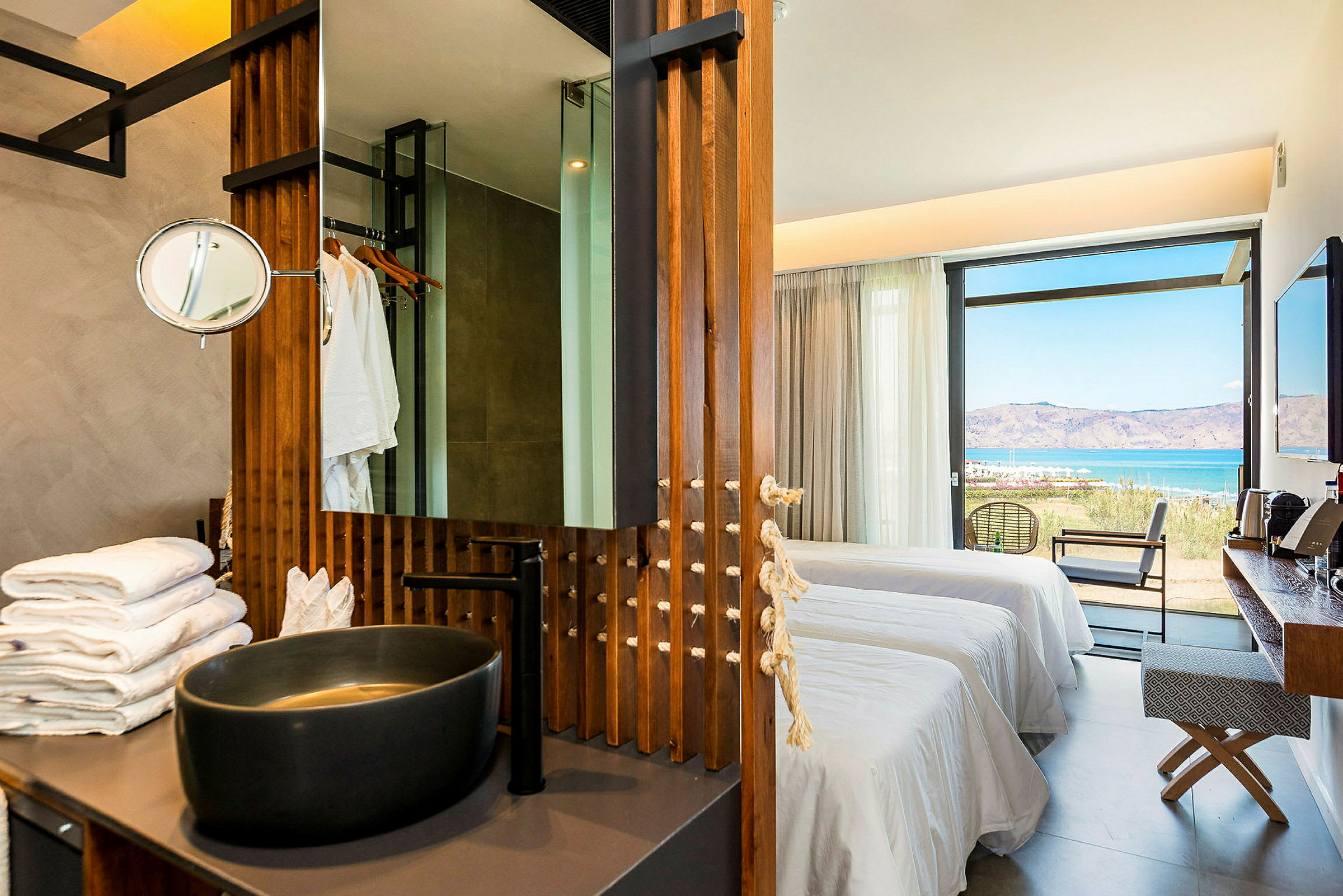 En modern hotellsvit med skålformad tvättställ, sängar och utsikt över havet. (AI-genererad text)