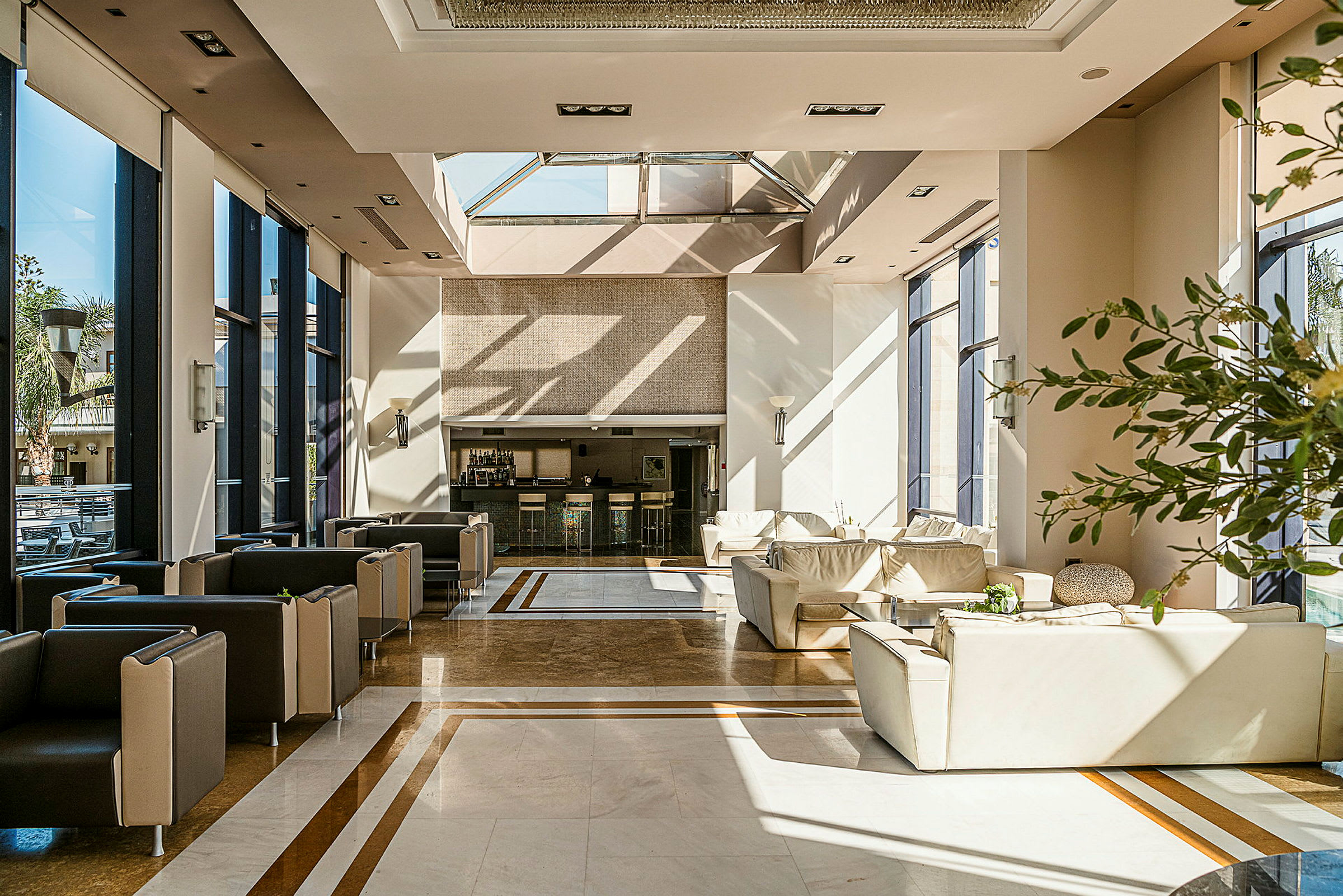 Ett ljust och modernt inrett hotellobby med stora fönster, bekväma sittmöbler och en reception. (AI-genererad text)