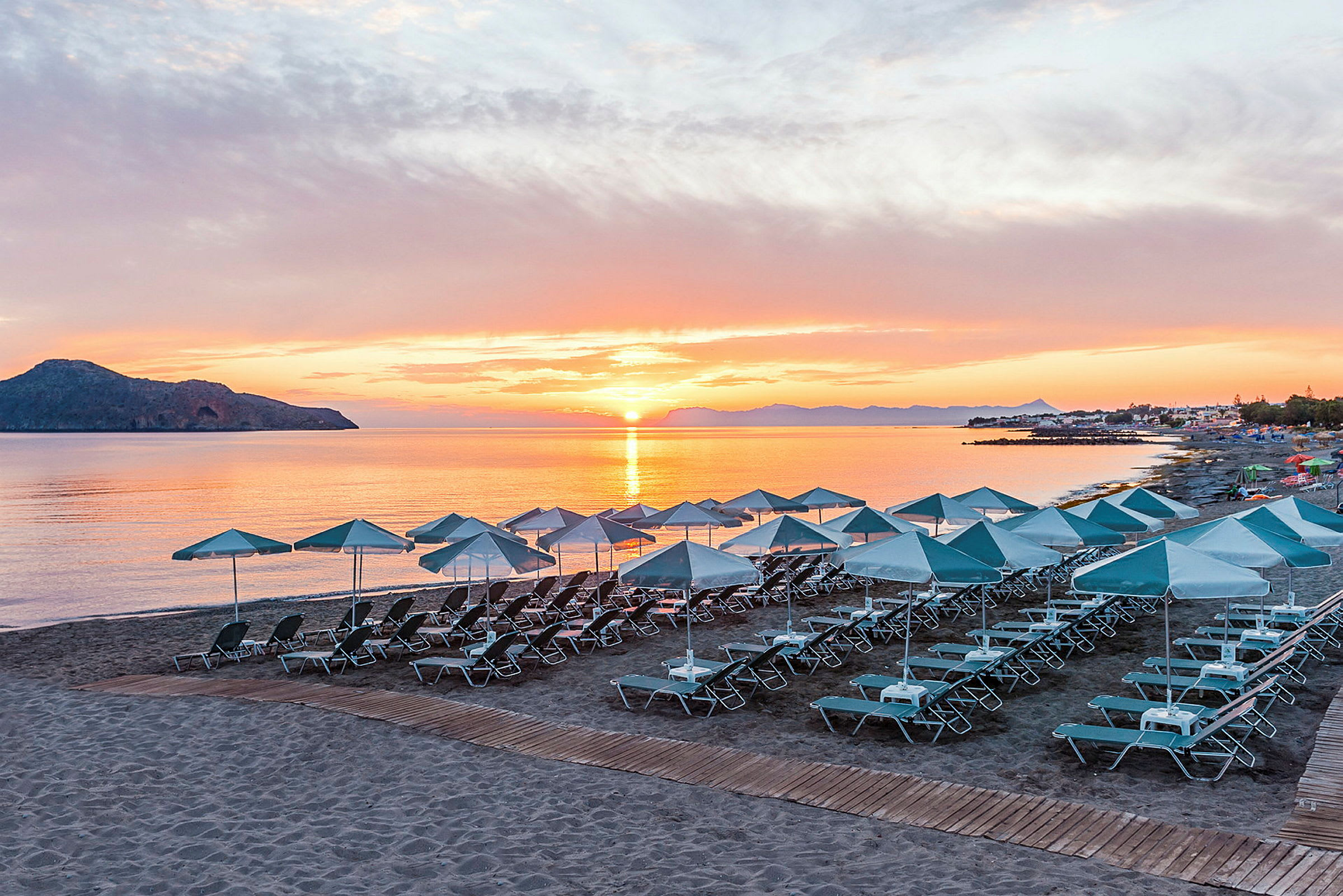 Strand med solstolar och parasoller vid solnedgång. (AI-genererad text)