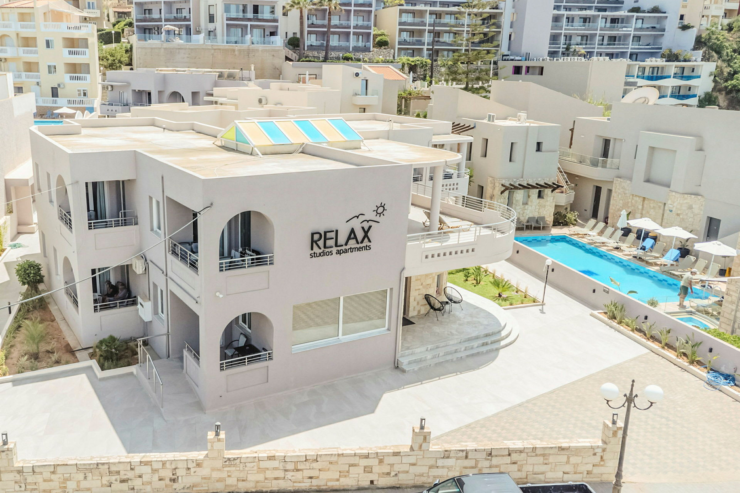 Utomhusmiljö vid Relax Studios Apartments, med pool och solstolar. (AI-genererad text)