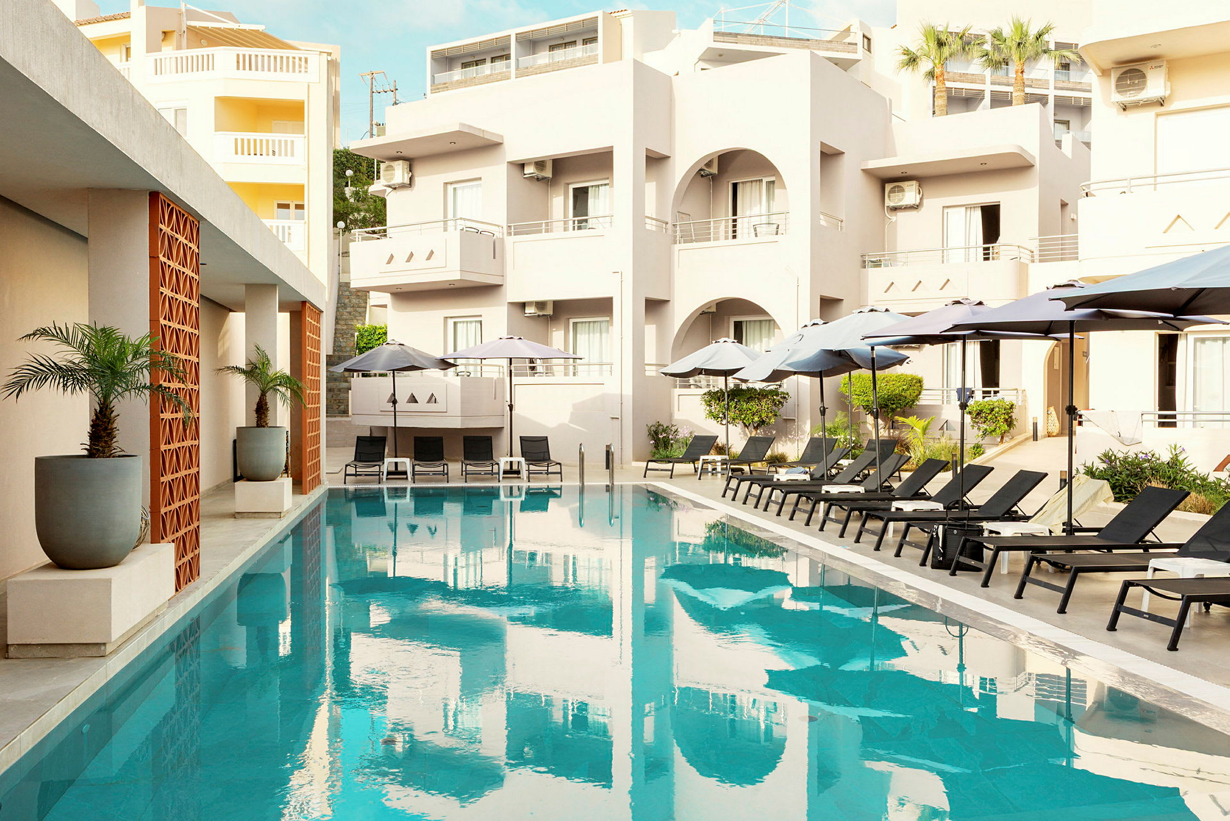 En utomhuspool med solstolar och parasoller vid ett hotell. (AI-genererad text)